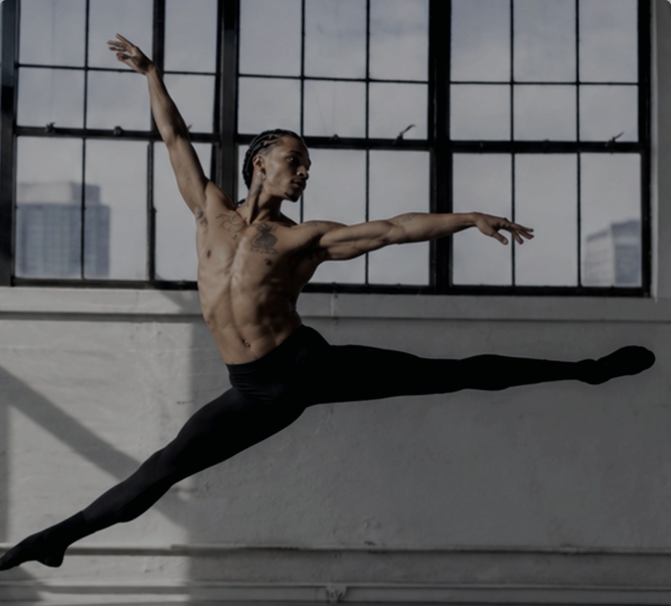 Dancer leaping across a window-lit studio