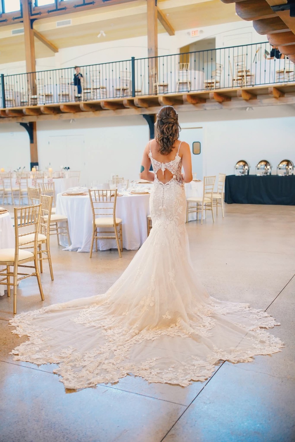 Bride seen from behind with a romantic half-up hairstyle and a sweeping lace train