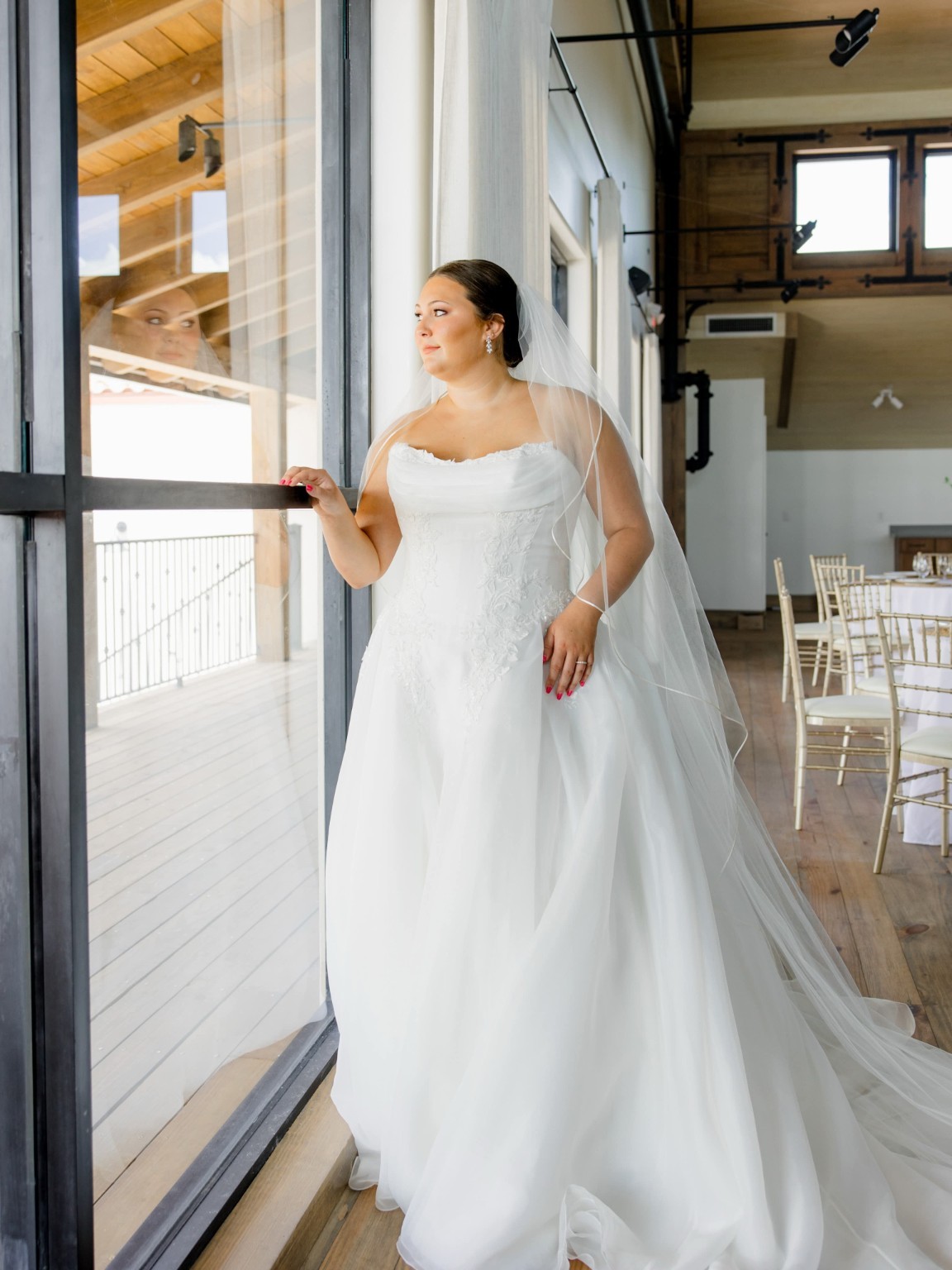 Bride with an elegant updo and veil beside a sunlit window