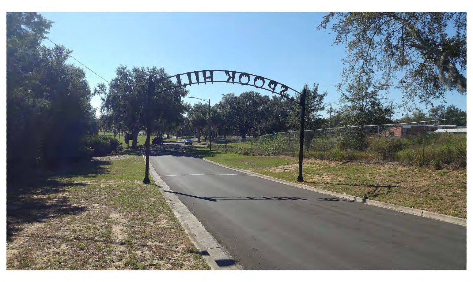 Reverse side of the Spook Hill archway with the road extending south toward trees