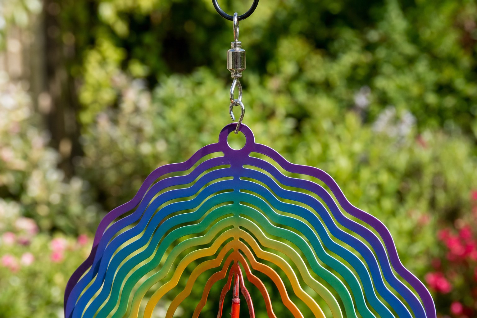 Wind spinner hanging loop and swivel connector against a garden background