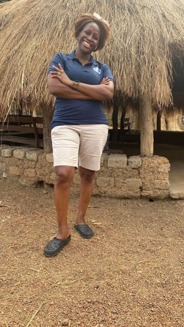 A volunteer standing outside a thatched building