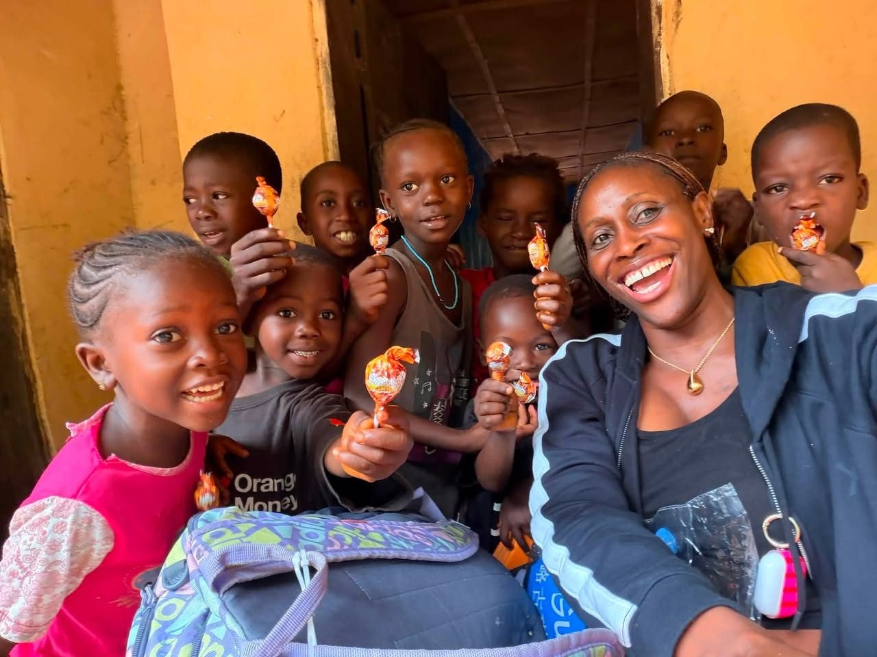 Smiling children gathered with a MaCHO team member