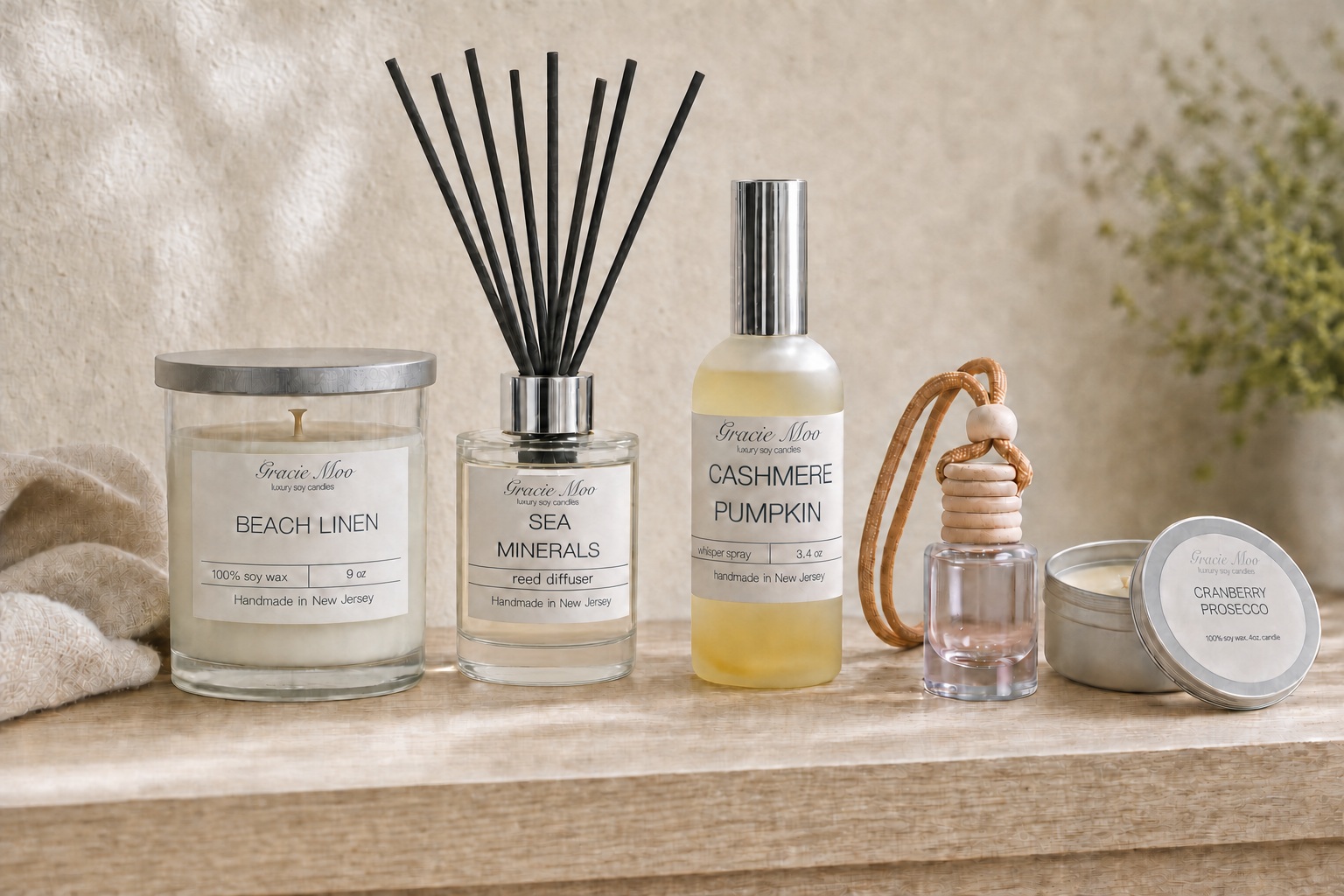 Gracie Moo candle, reed diffuser, Whisper Spray, hanging diffuser and travel tin arranged on a wooden tabletop