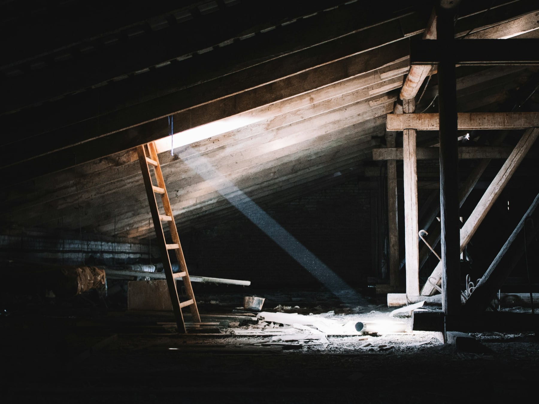 Wooden ladder in a dark attic lit by a shaft of light