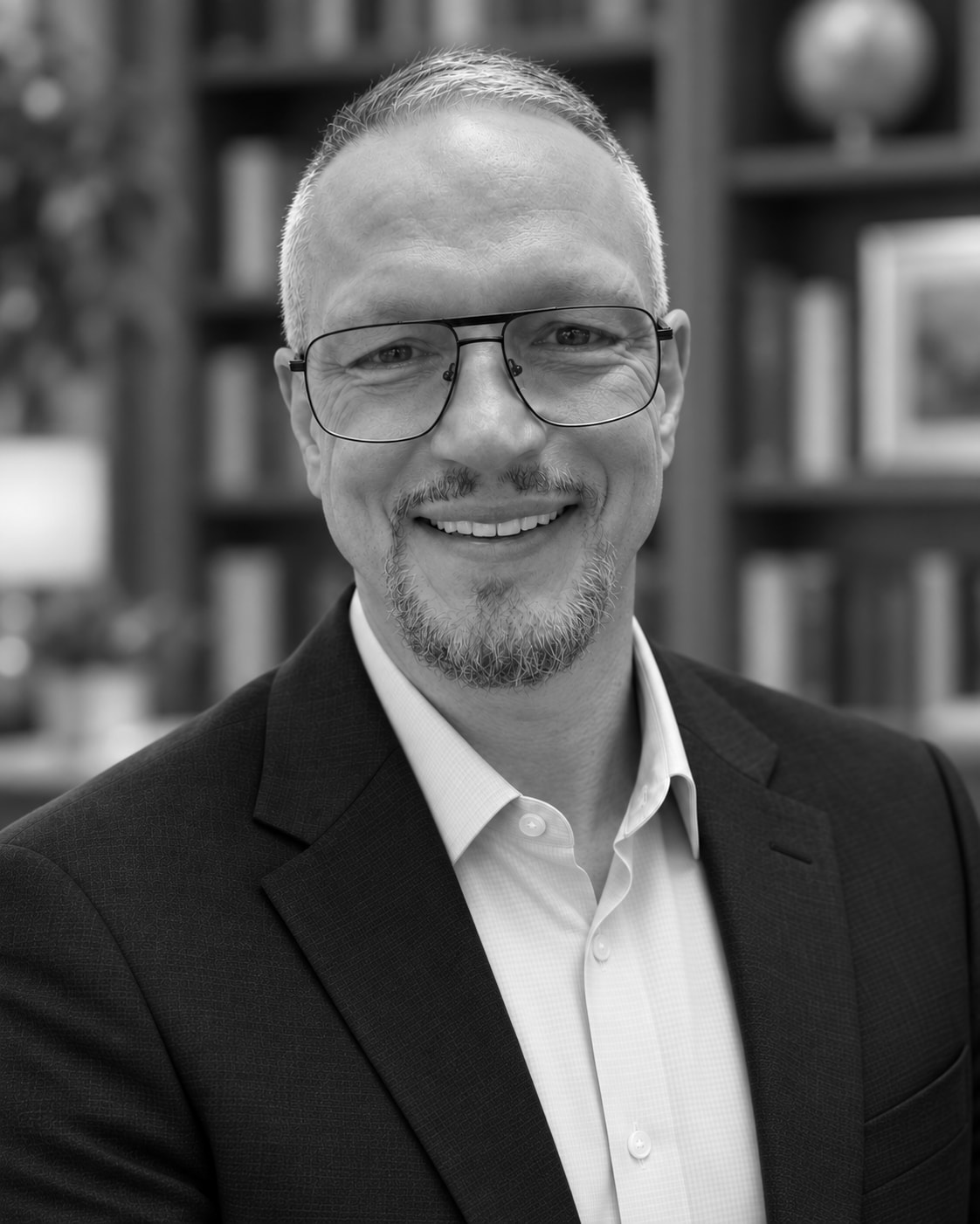 Black-and-white portrait of Stephen Deason before a bookshelf