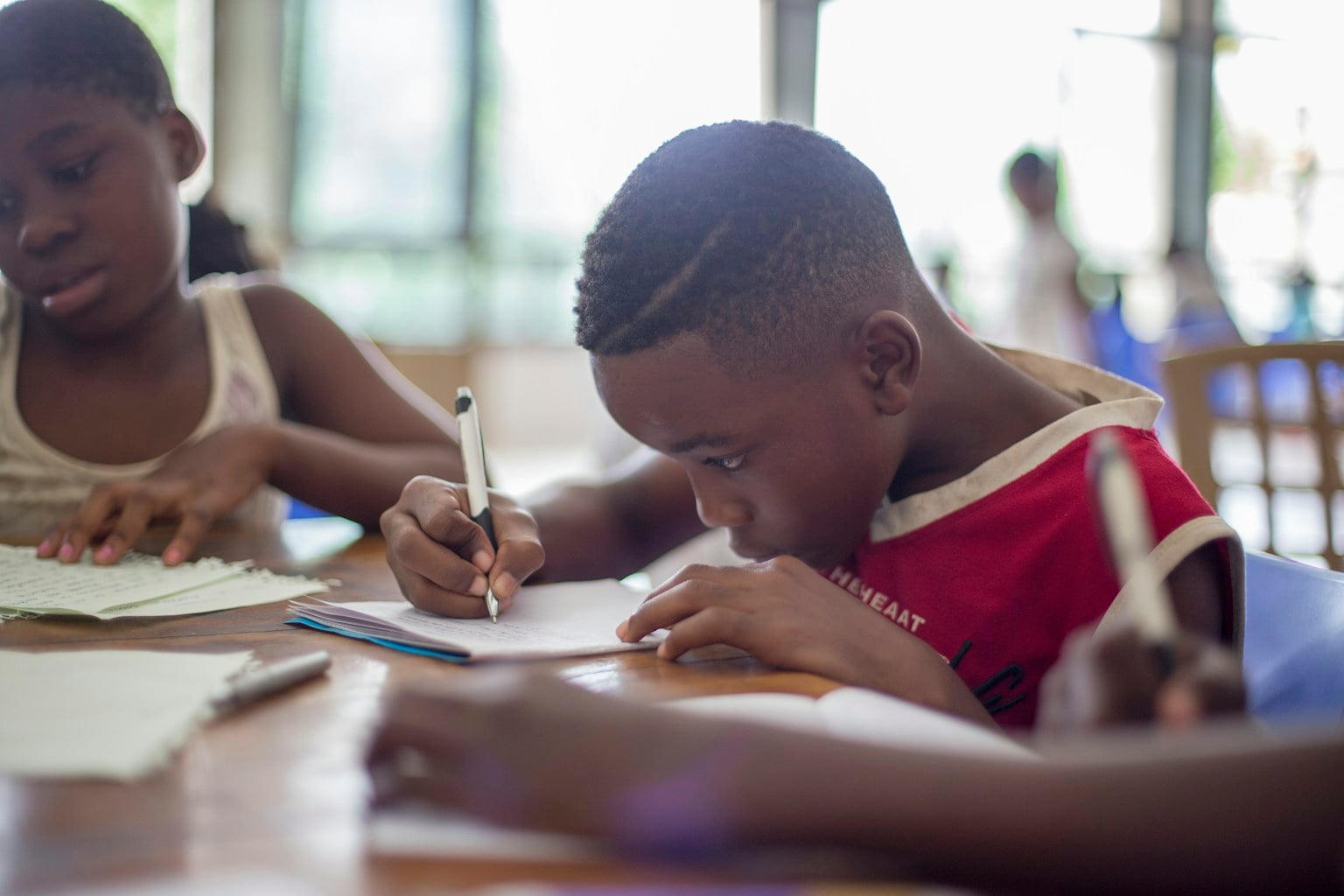 A teenager concentrating on schoolwork with an adult nearby