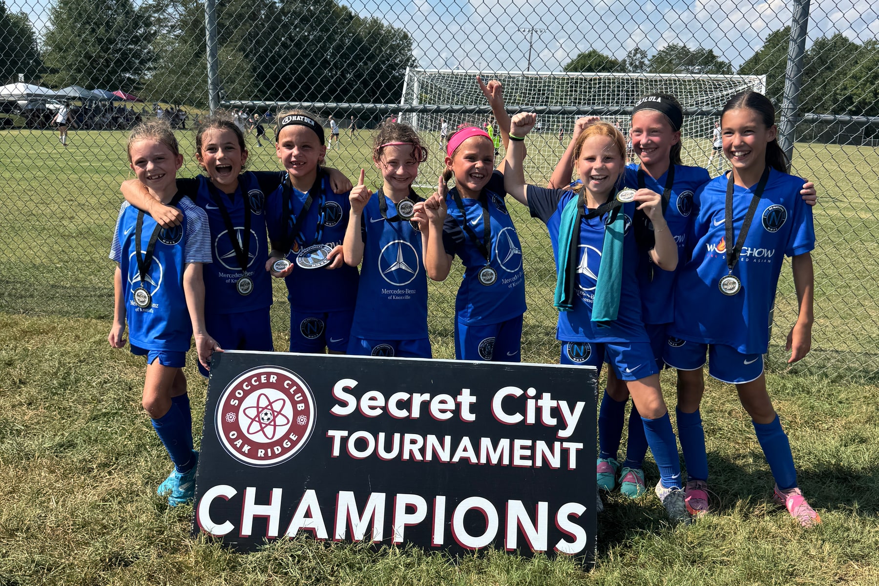 FC National U10 Girls celebrating their Secret City Tournament championship with medals and a champions sign