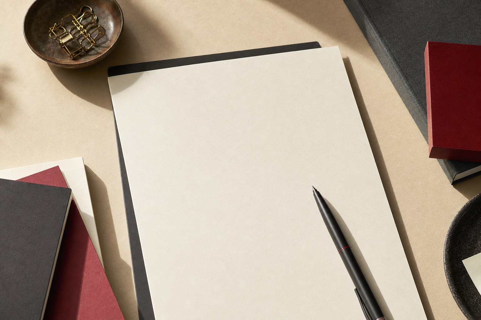 A blank cream resume page with a pen and organized work materials