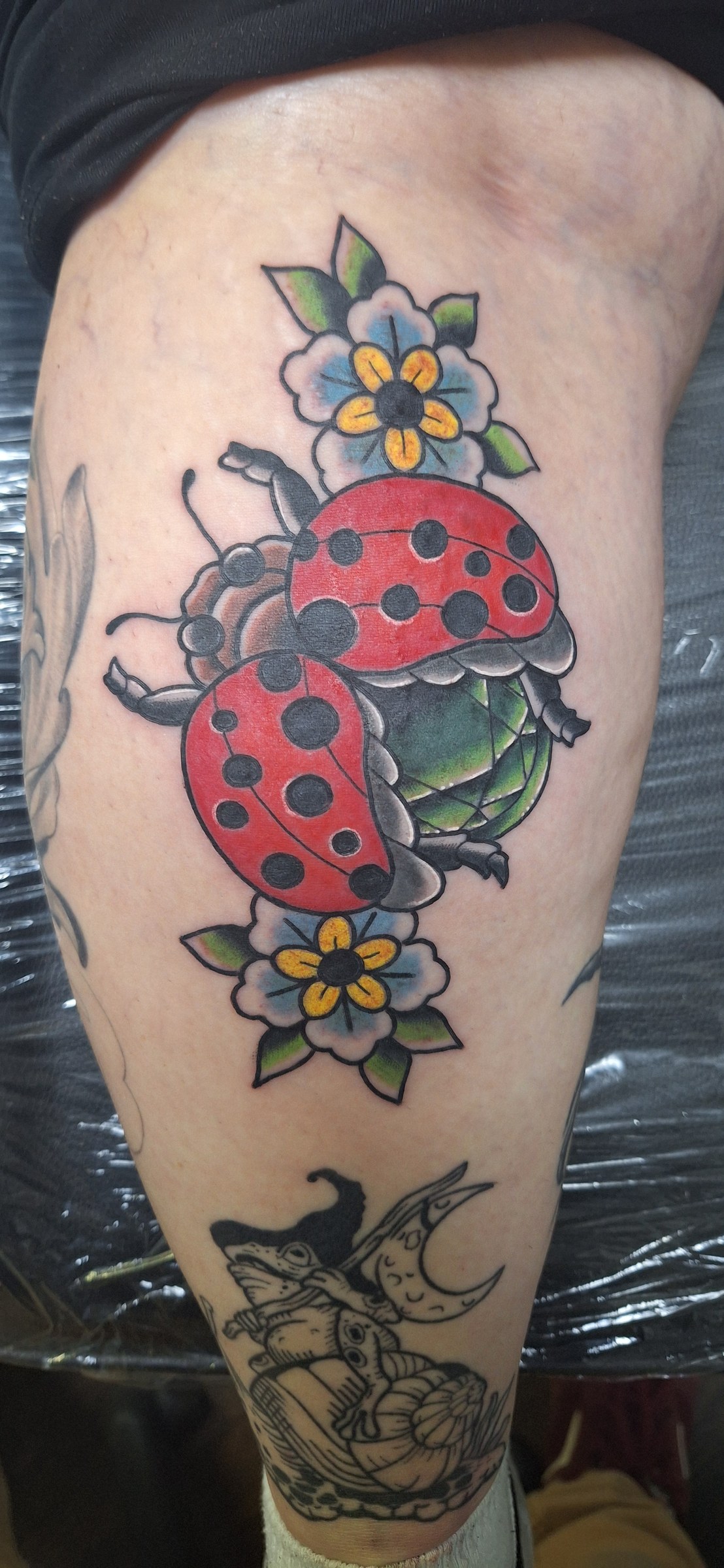 Colorful ladybugs and flowers tattoo by Rob Scotti