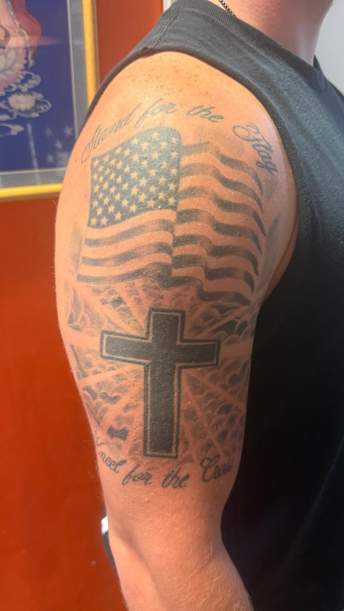 American flag and cross upper-arm tattoo by Joe Kennedy