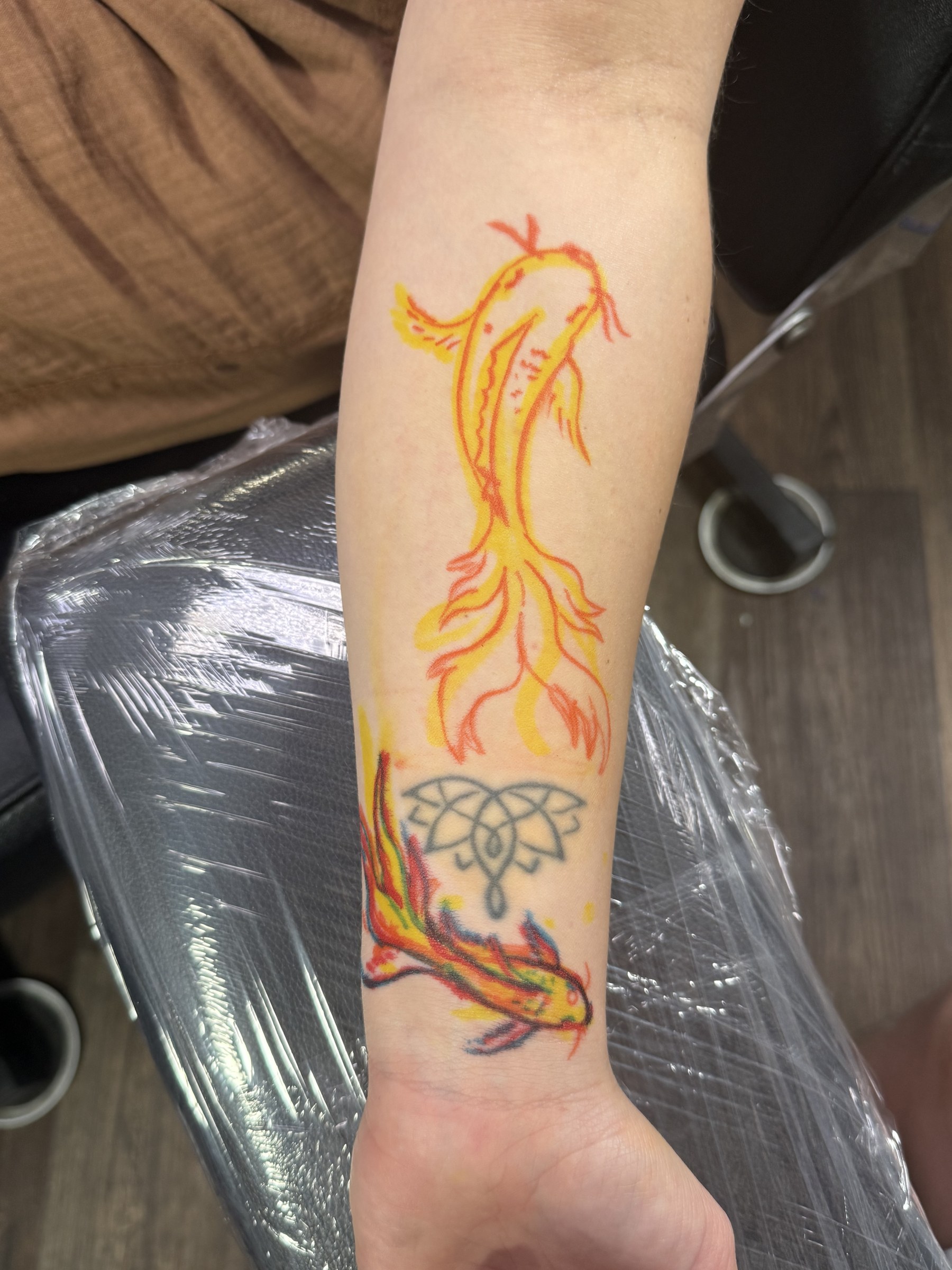 Colorful bird and flower forearm tattoo by Joe Kennedy