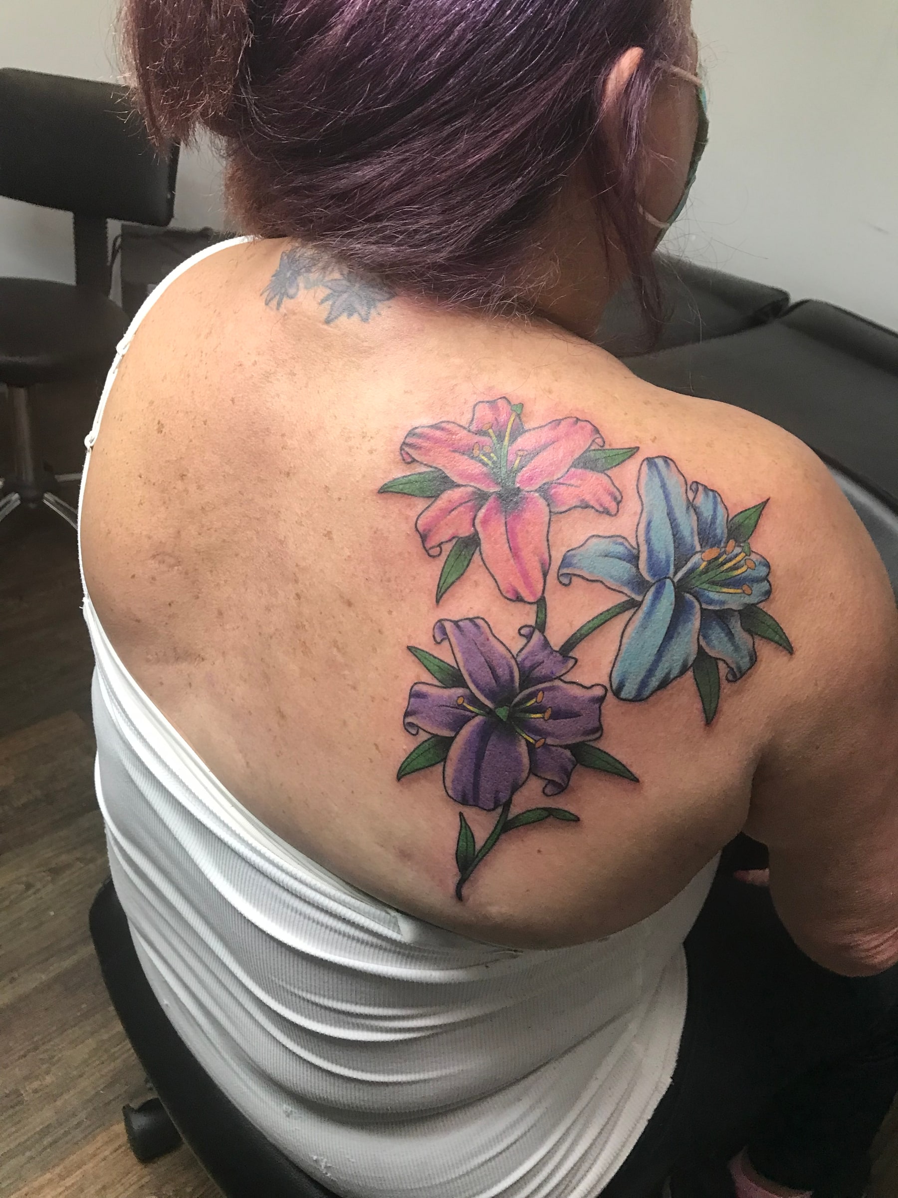 Colorful lily shoulder tattoo by Rob Scotti