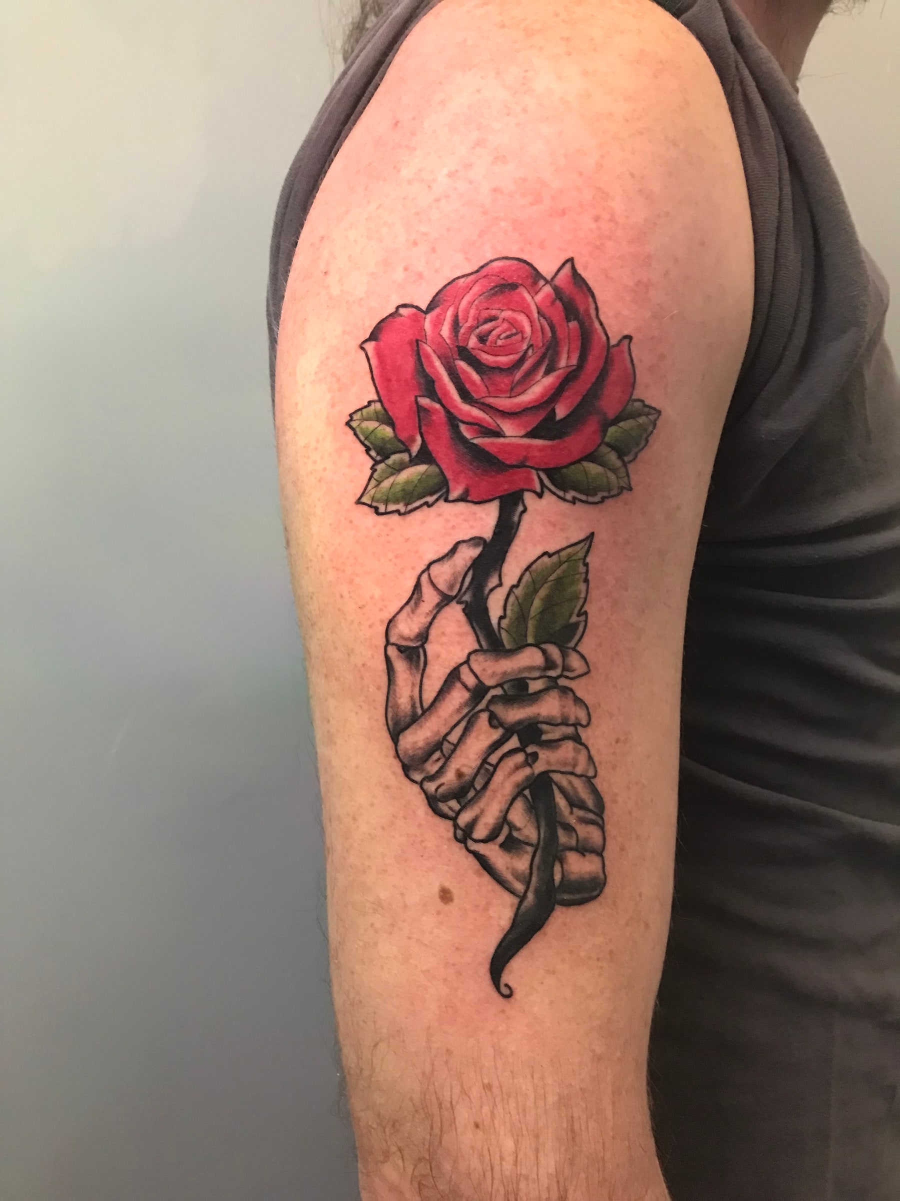 Skeletal hand holding a red rose tattoo by Rob Scotti