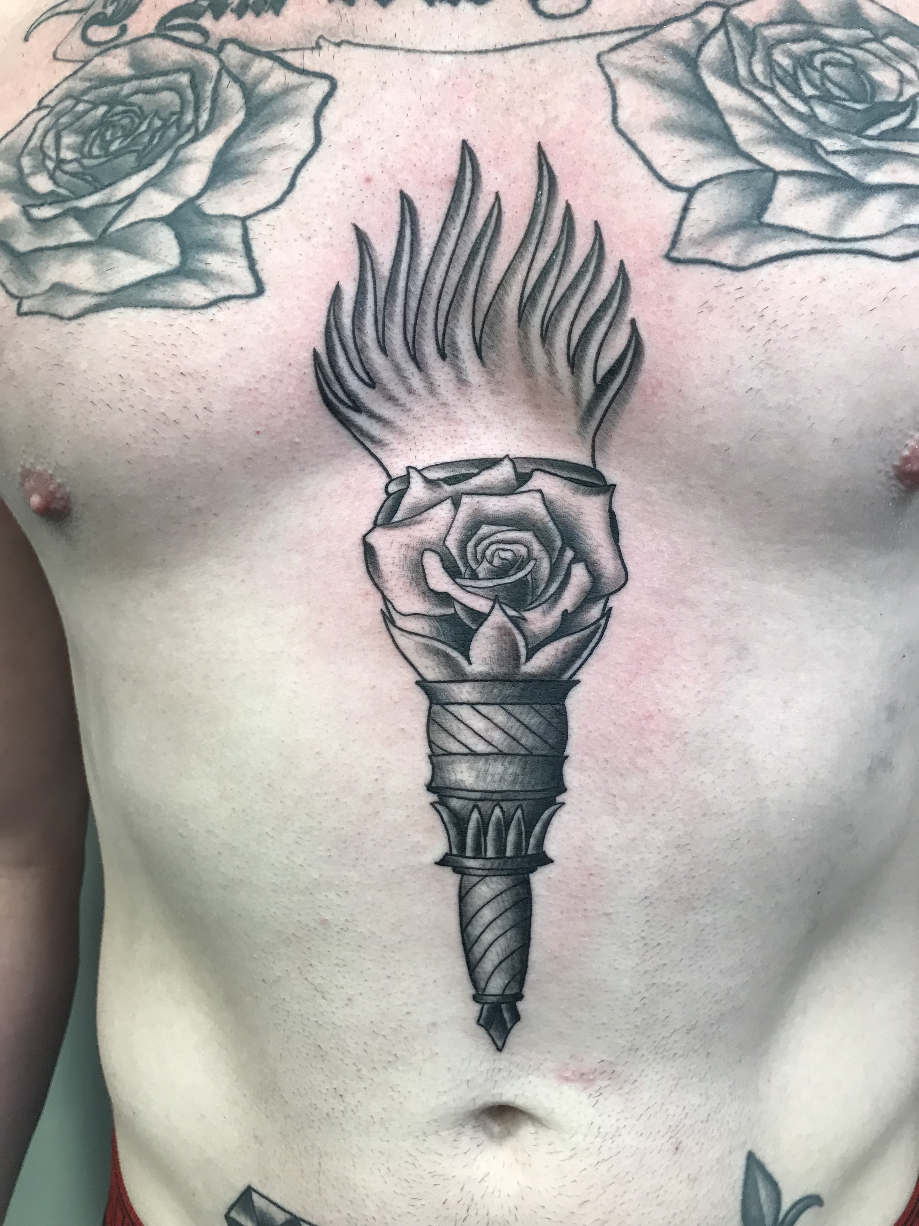 Black and gray rose torch chest tattoo by Rob Scotti