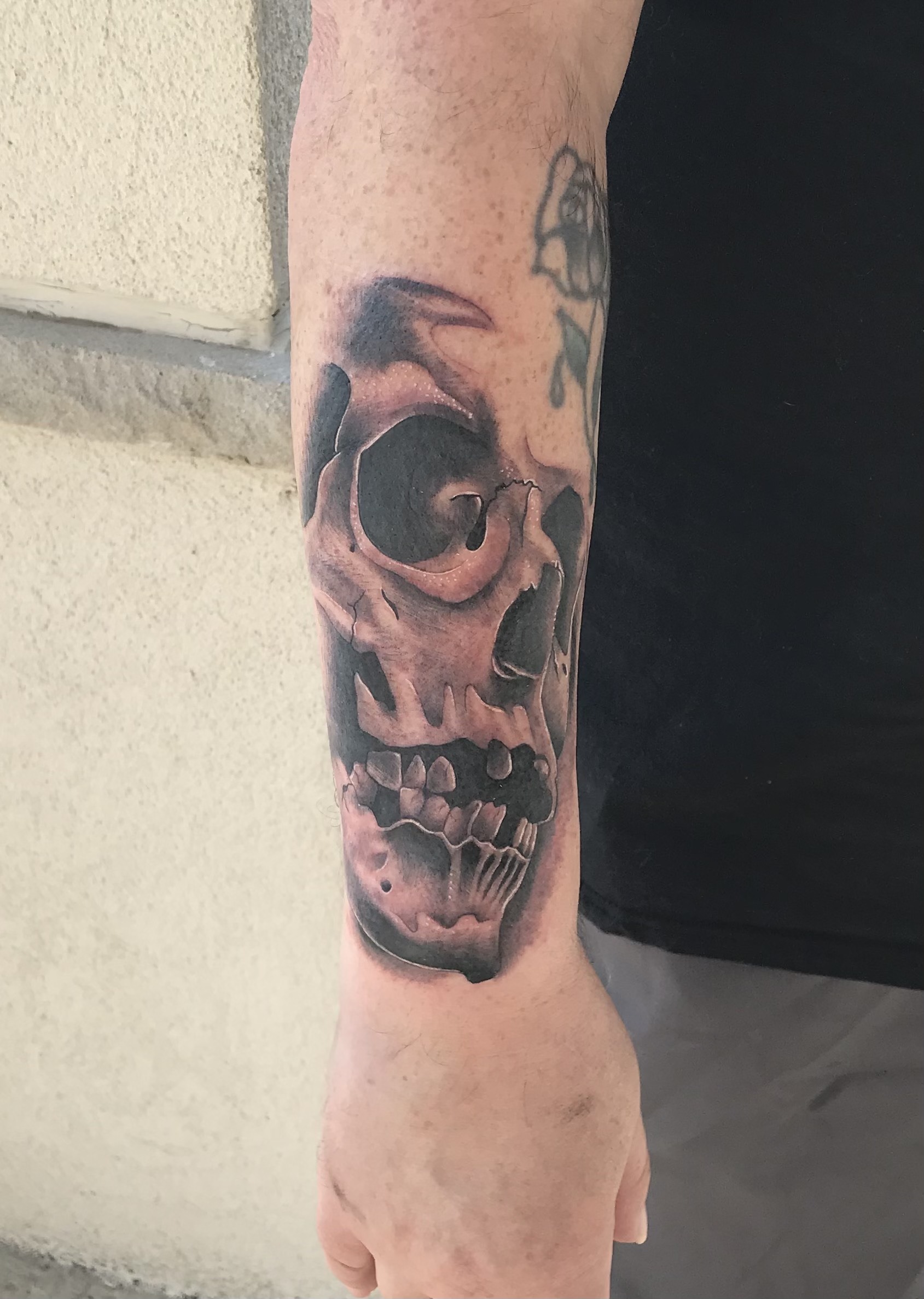 Black and gray skull forearm tattoo by Rob Scotti