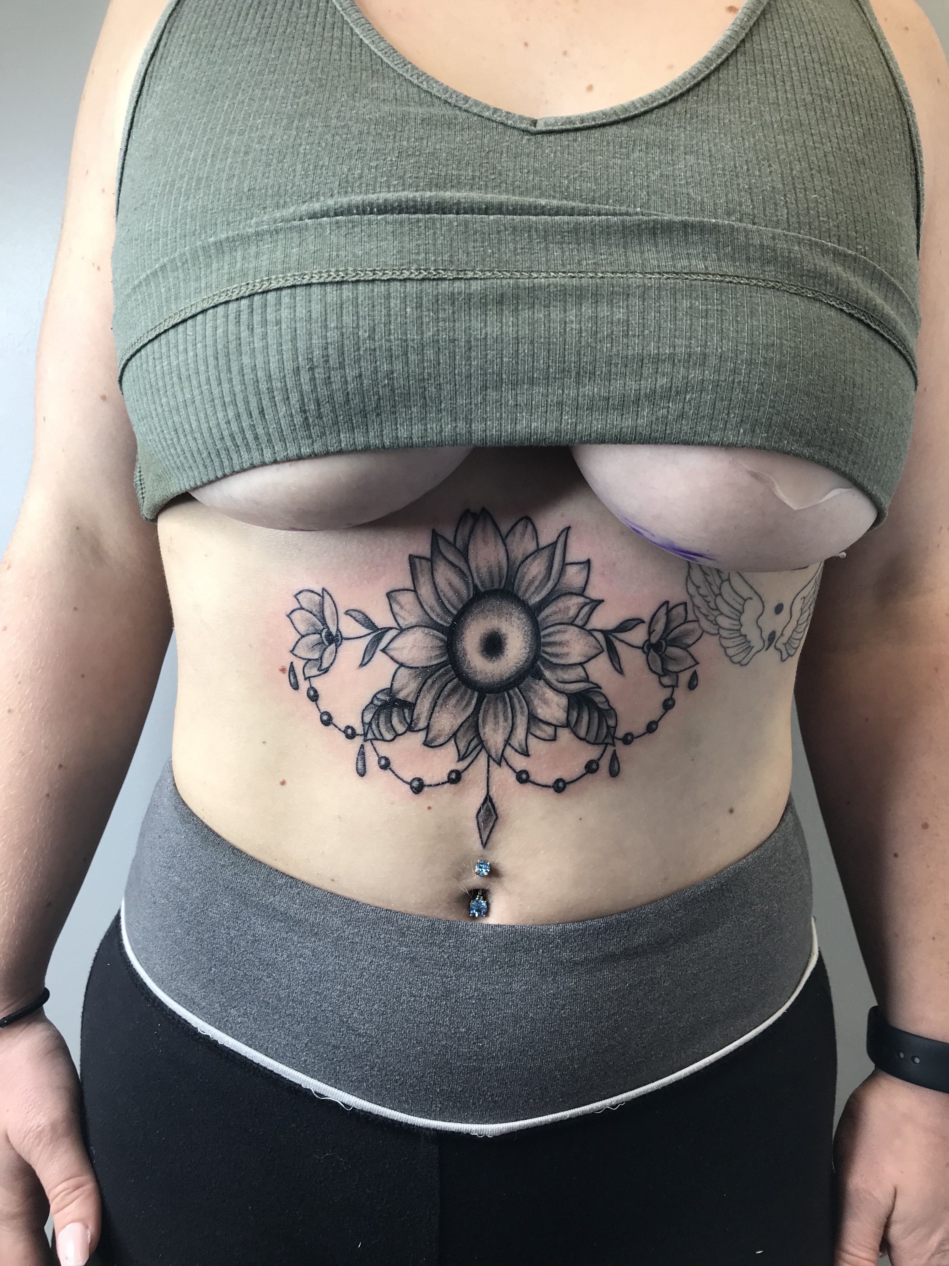 Black and gray sunflower ornamental underboob tattoo by Rob Scotti