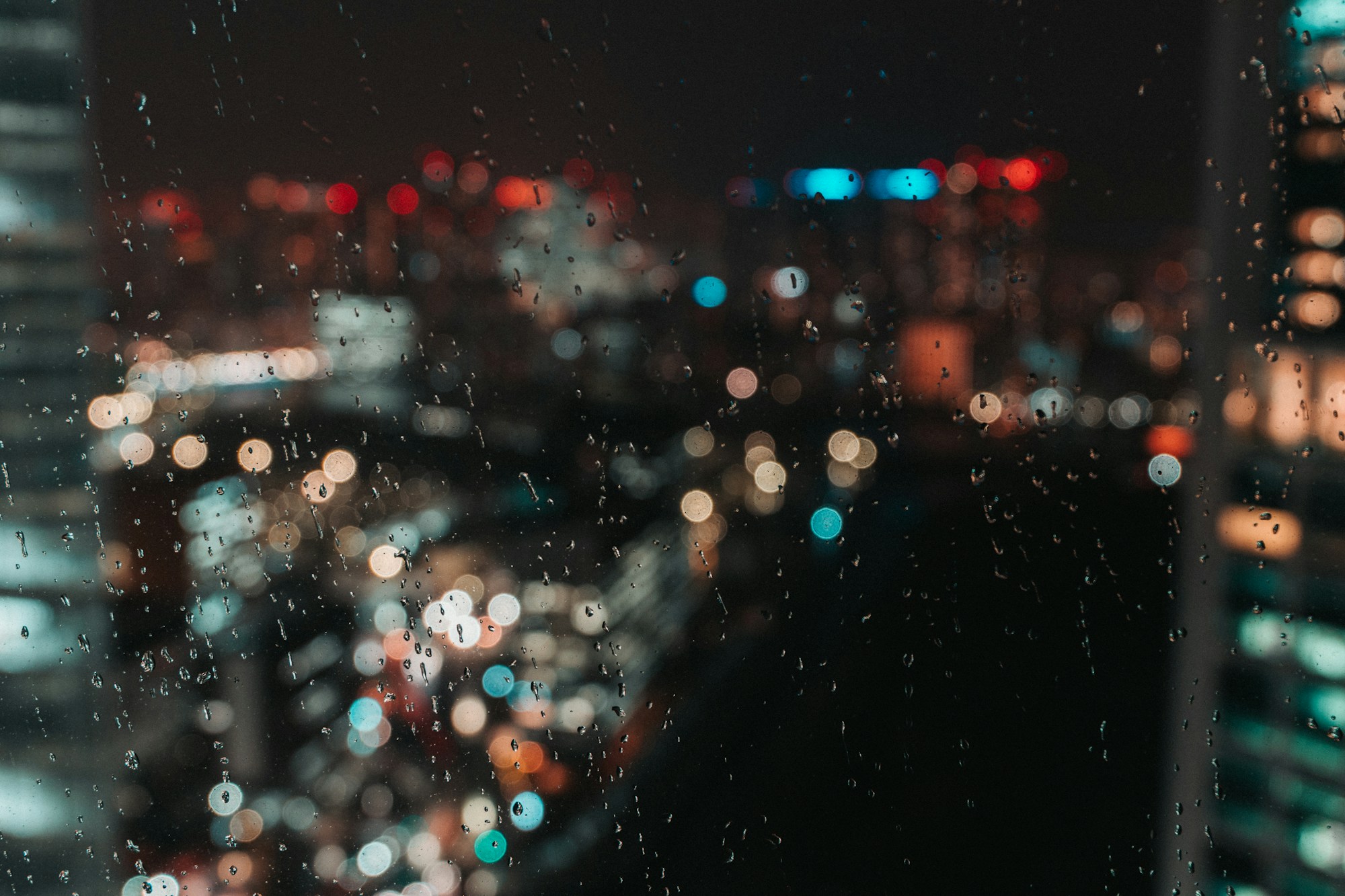 Rain drops on a window with city lights blurred in the background