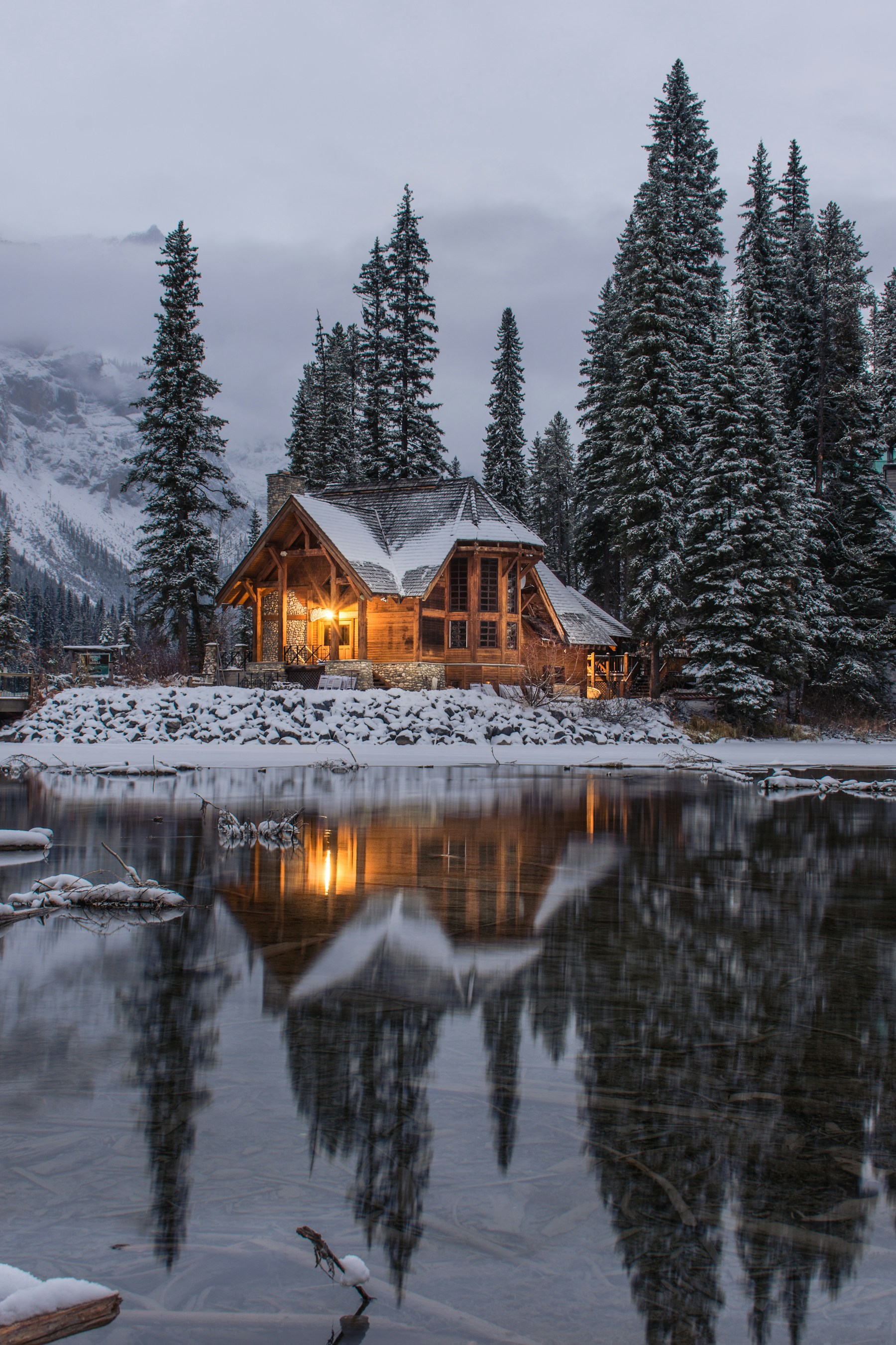 A warmly lit cabin beside a winter lake