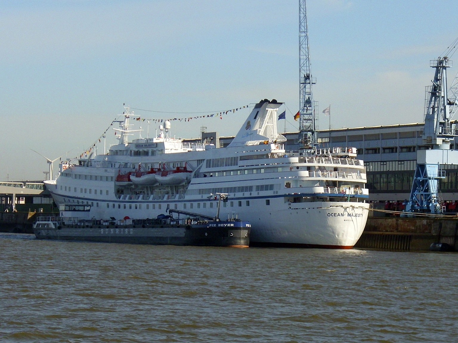 Cruise ship viewed from a harbour under a bright sky