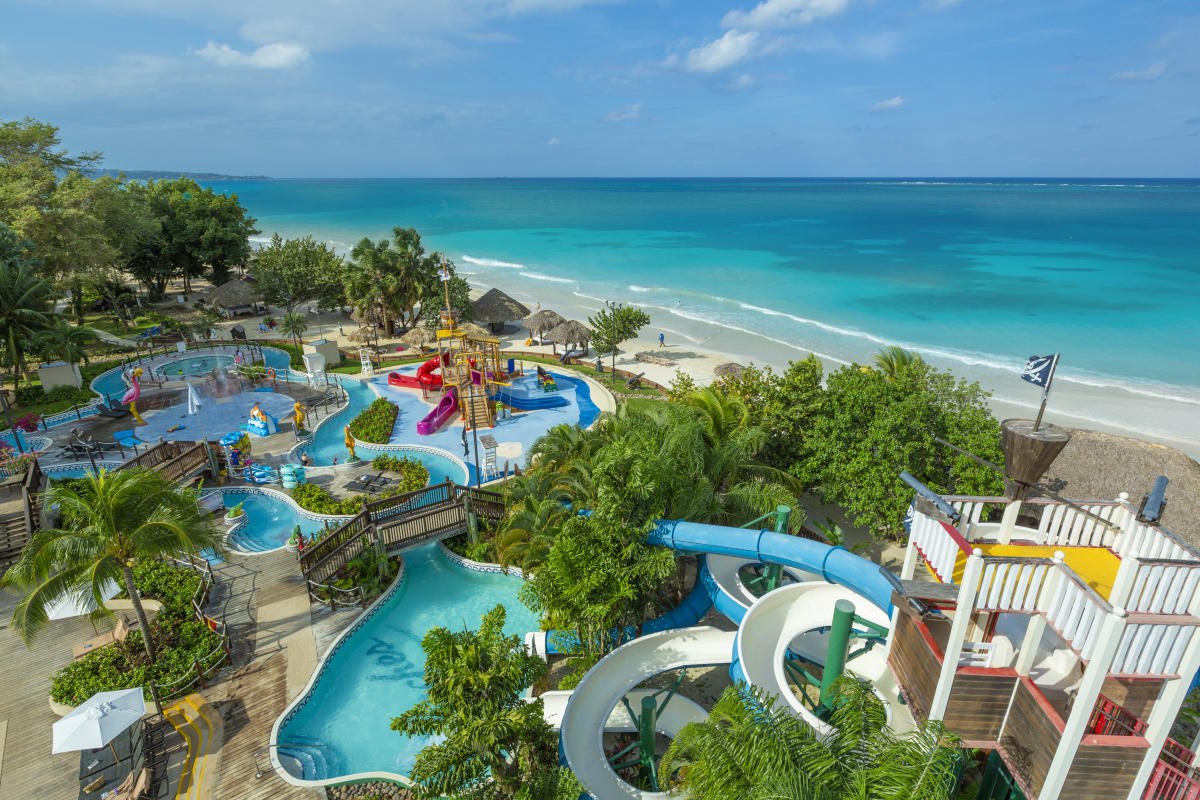 Aerial view of a beachfront waterpark with pools, waterslides, and turquoise Caribbean water