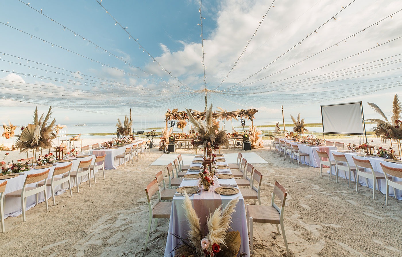 Beachfront destination wedding reception with decorated tables beneath string lights