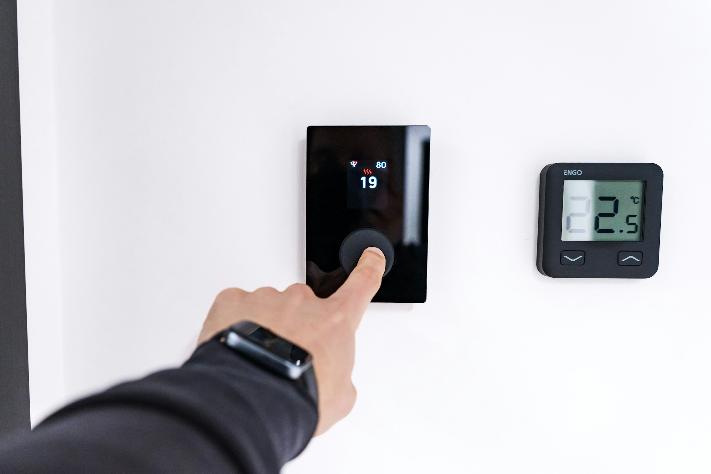 Person adjusting a wall temperature controller