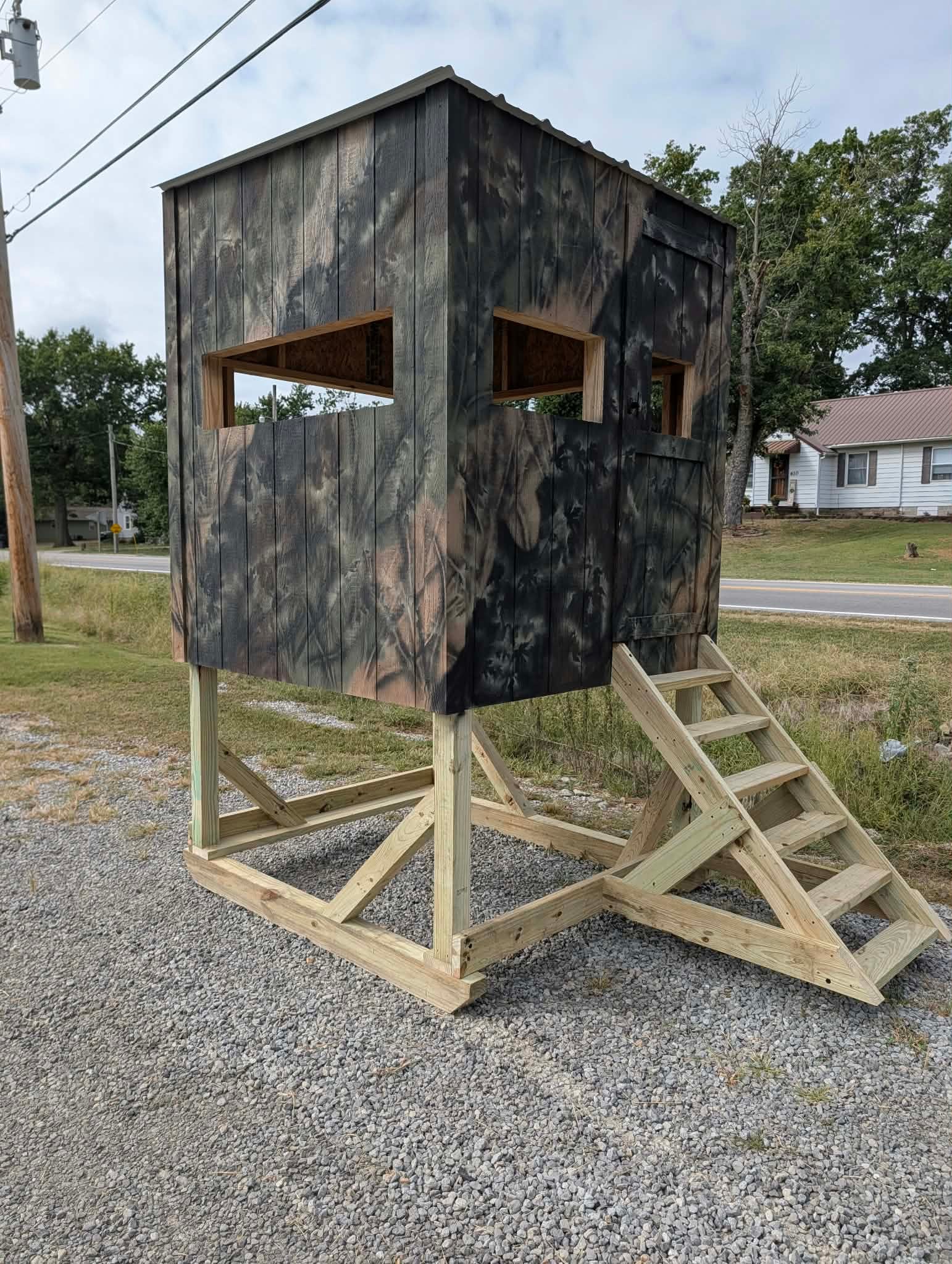 Angled exterior view of the Elite Outdoors camouflage hunting blind with elevated treated lumber base