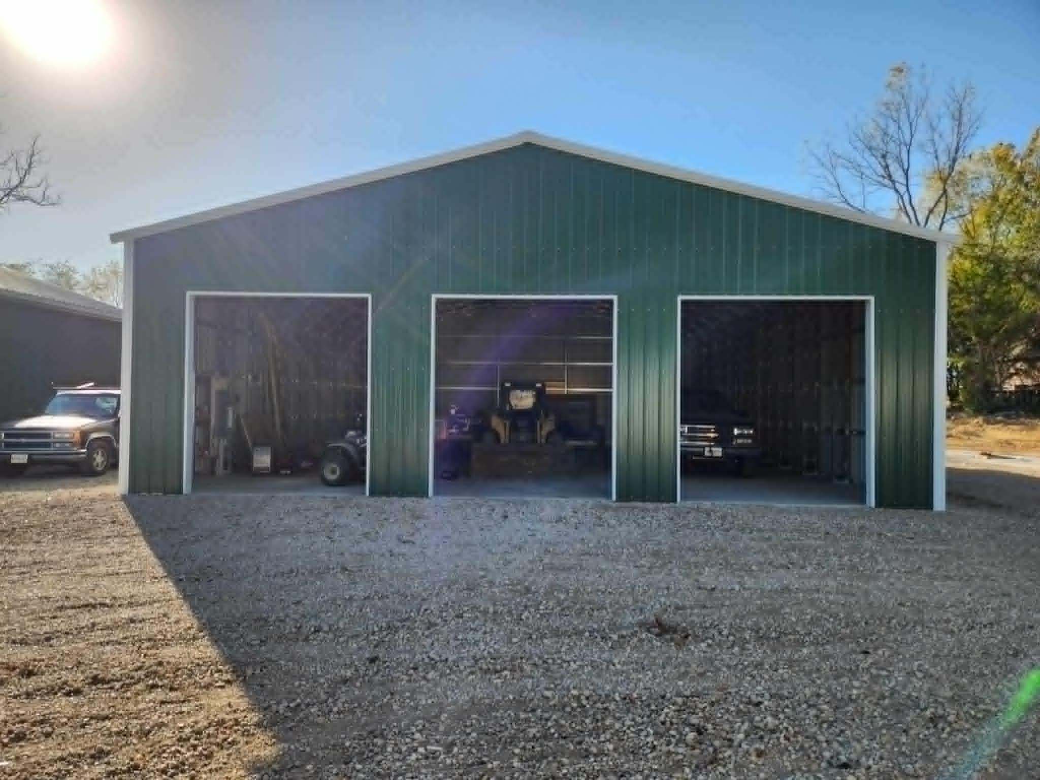 Large green steel garage with three open bays