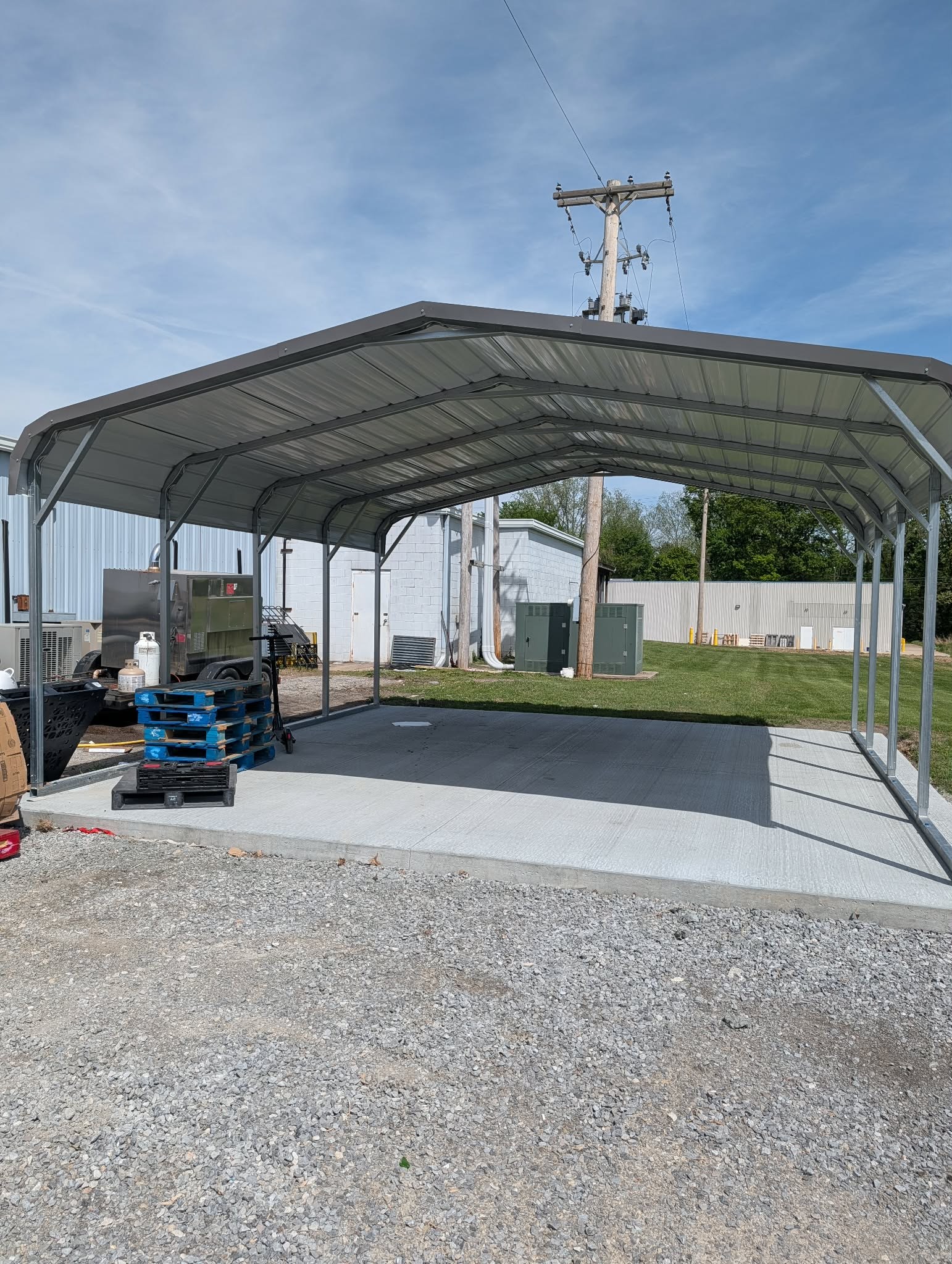 Open steel carport covering a concrete pad