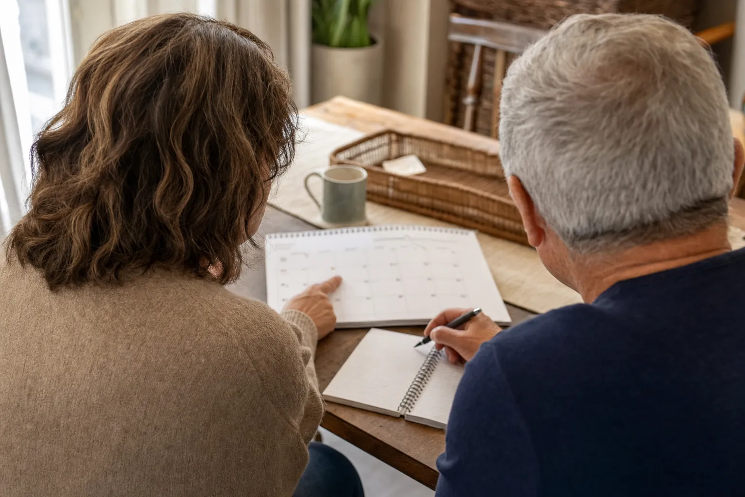 Two adults reviewing a calendar and notebook together at a table