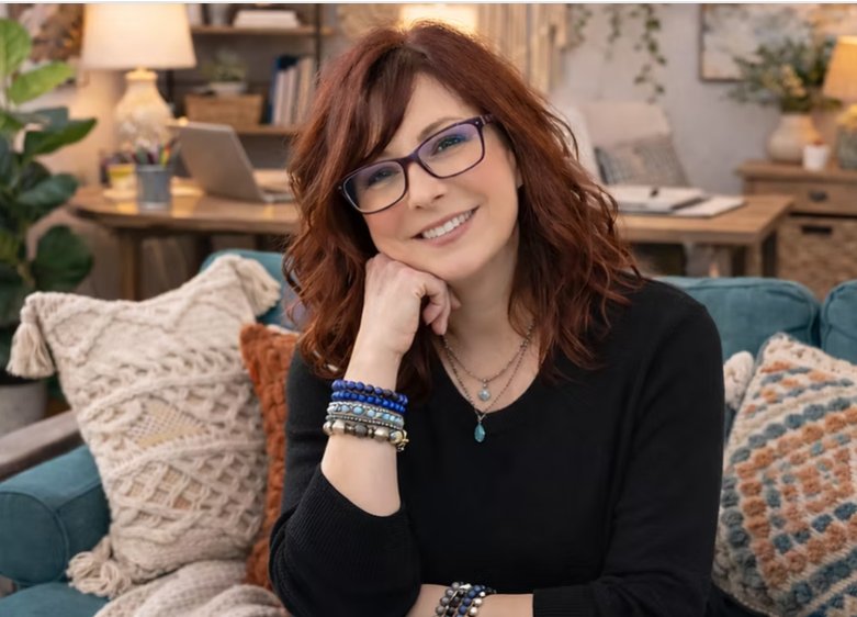Kristina Mumma smiling while seated on a teal sofa