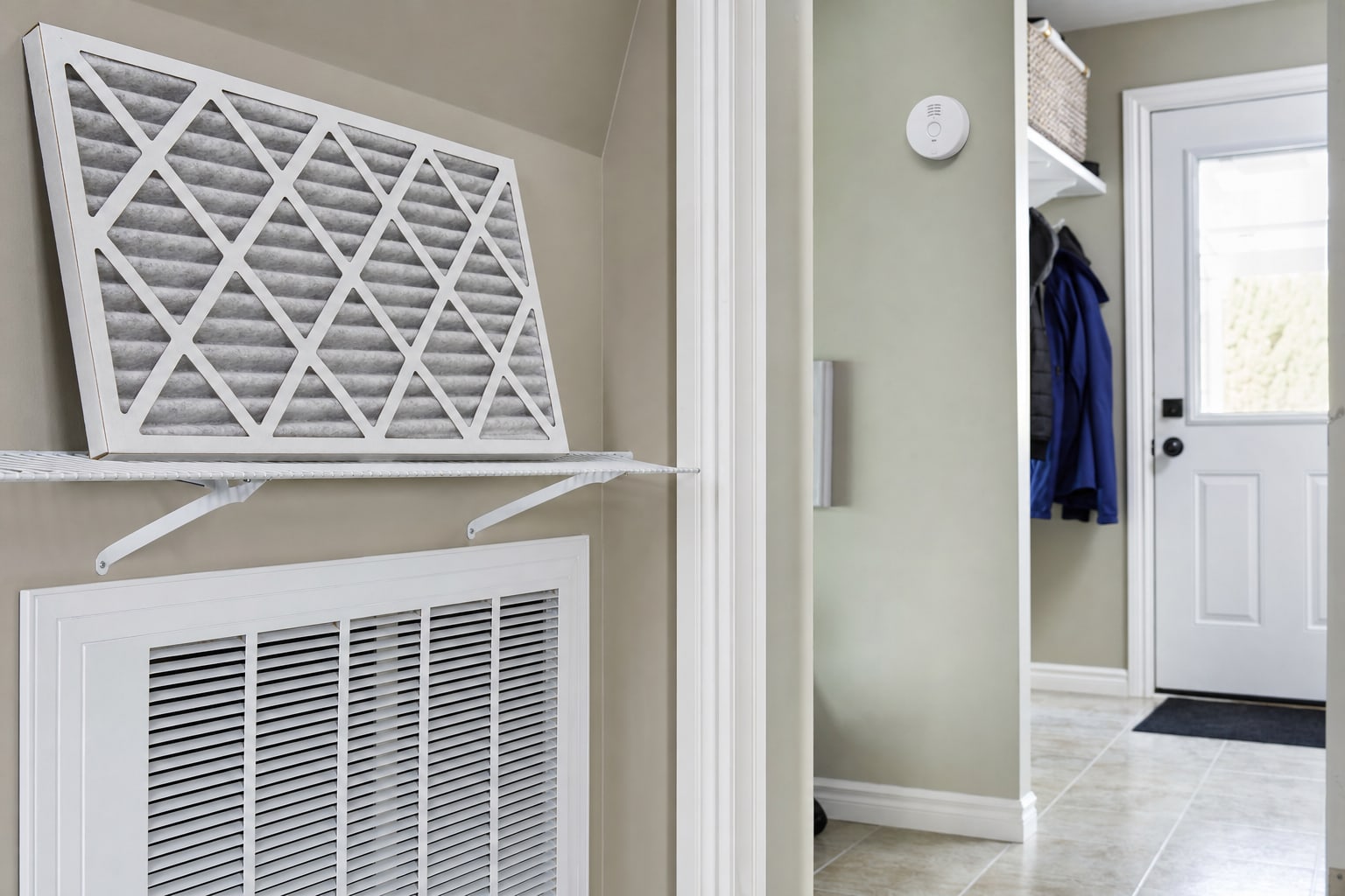 HVAC filter beside a return grille and smoke alarm in a home