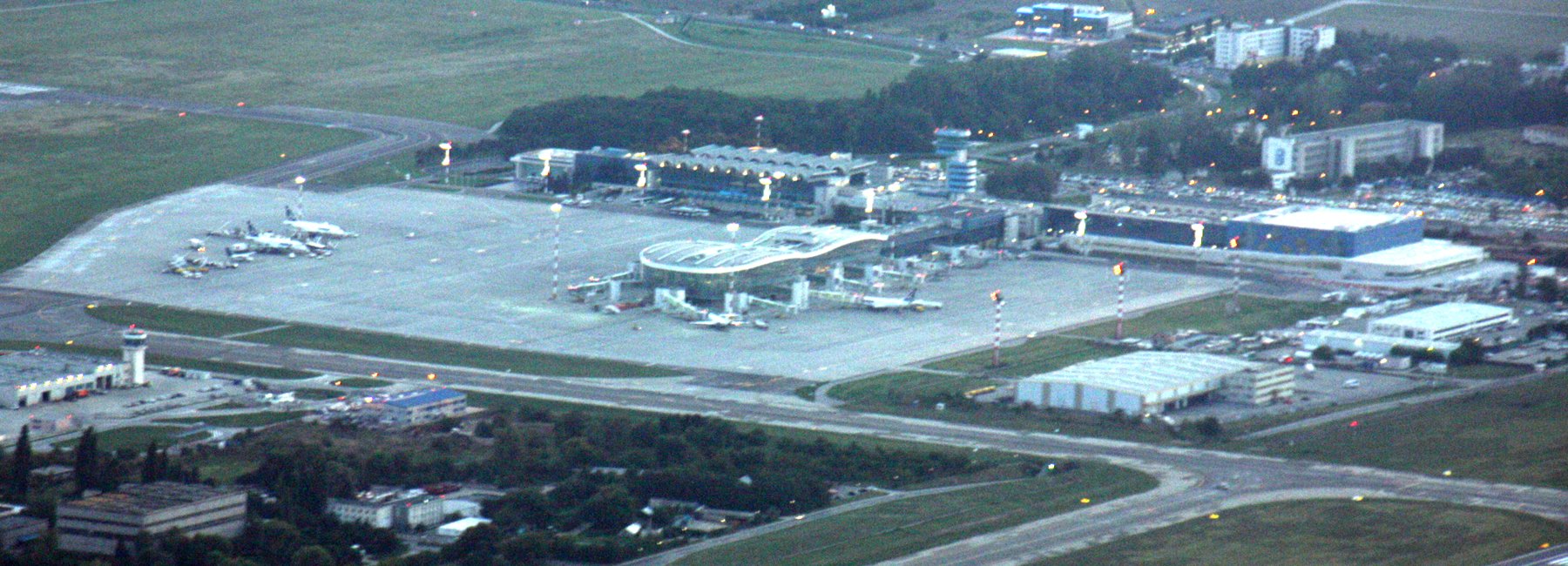 An aerial view of Henri Coandă International Airport in Otopeni, showing aircraft parked around the terminal gates