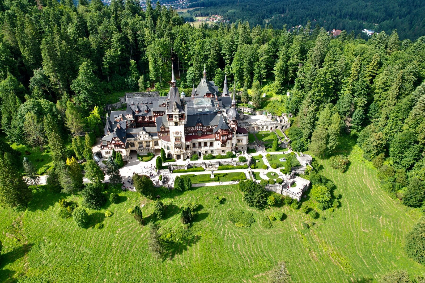Peleș Castle in Sinaia, with ornate towers, gardens, and forested hills