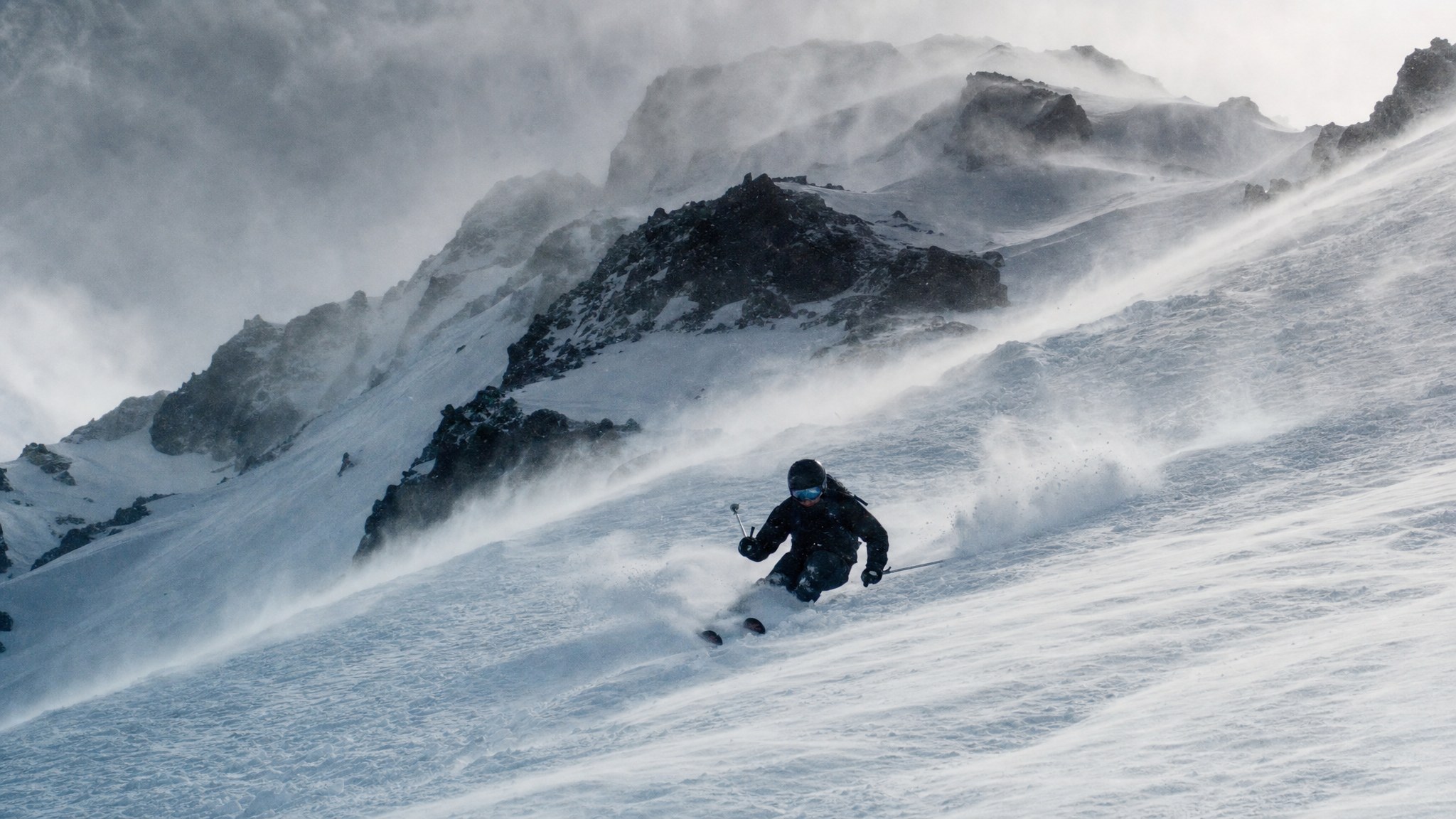 Skier descending a steep, stormy Mt. Hood slope
