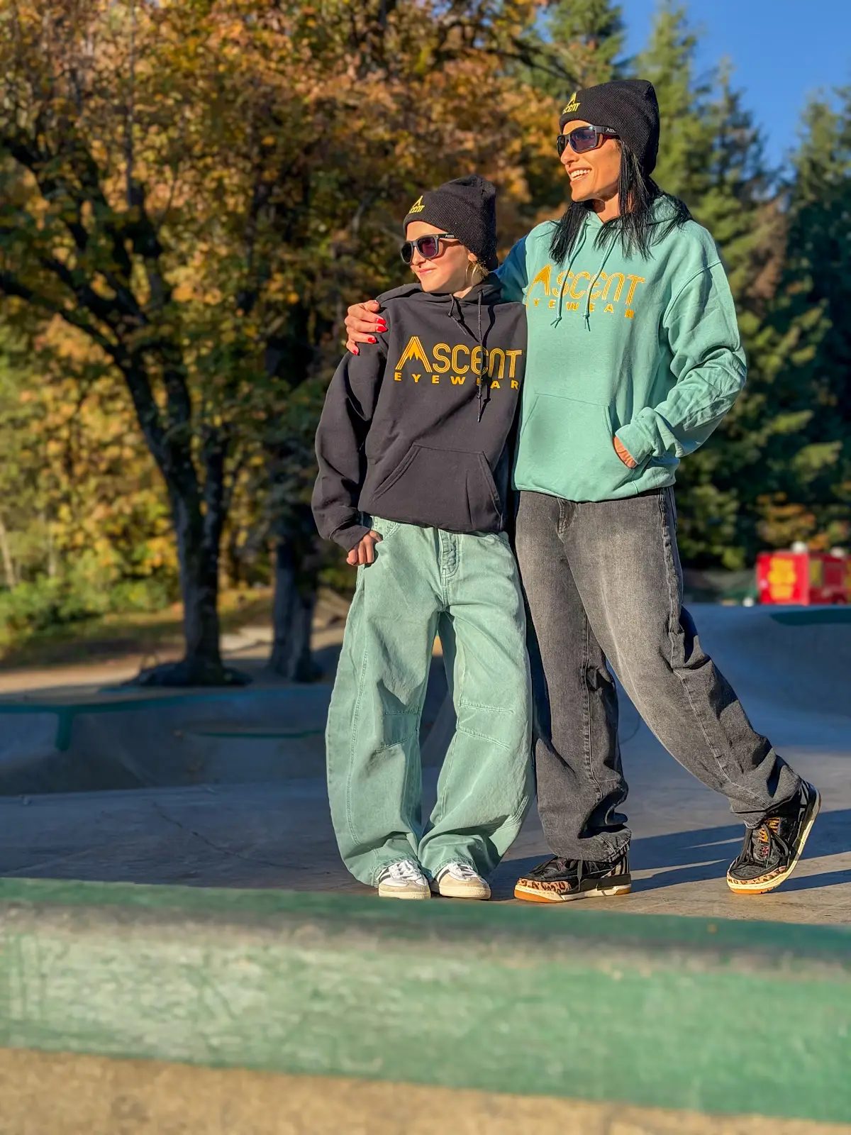 Two riders wearing Ascent beanies and hoodies at a skatepark
