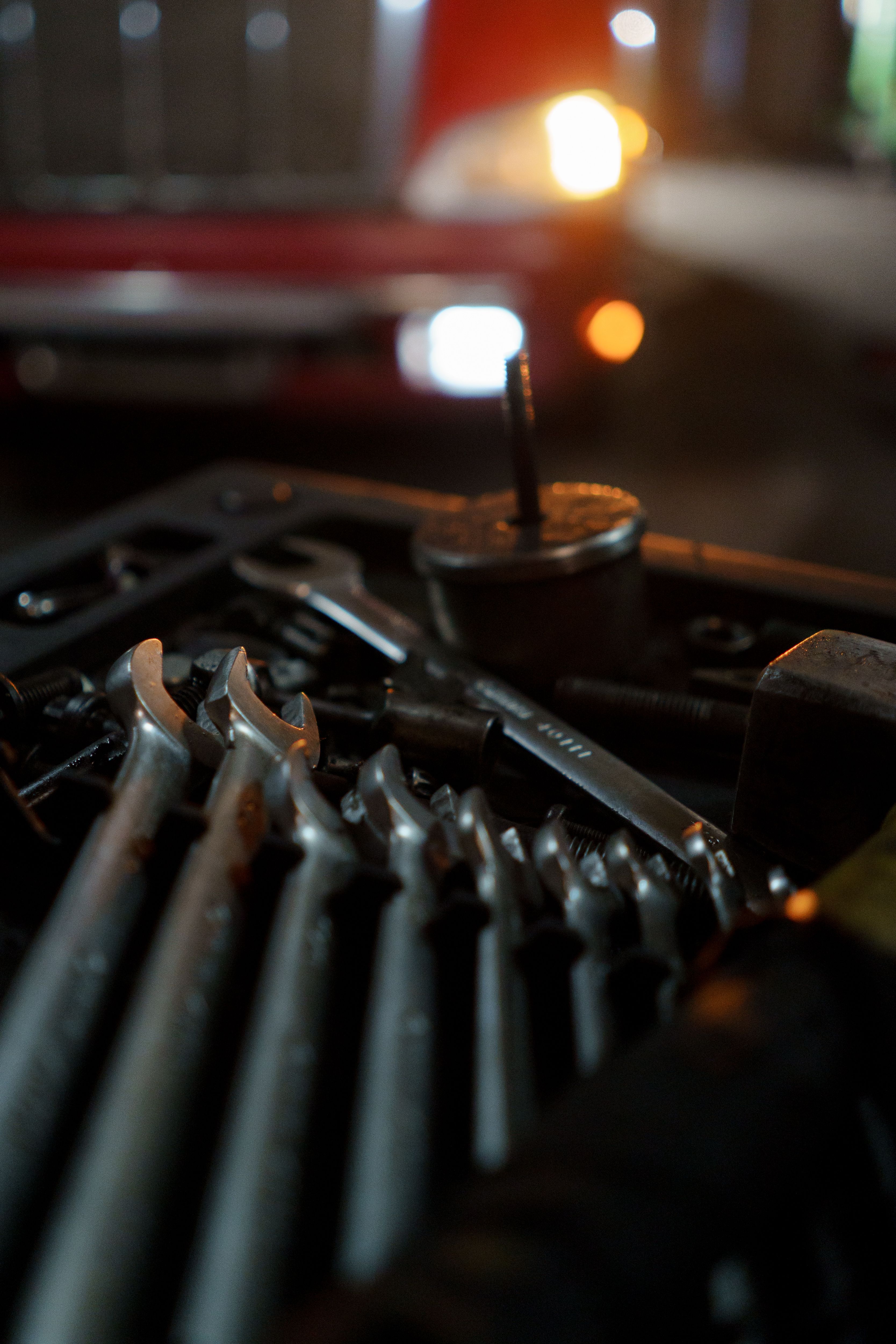 Hand tools set out in front of a car in a garage