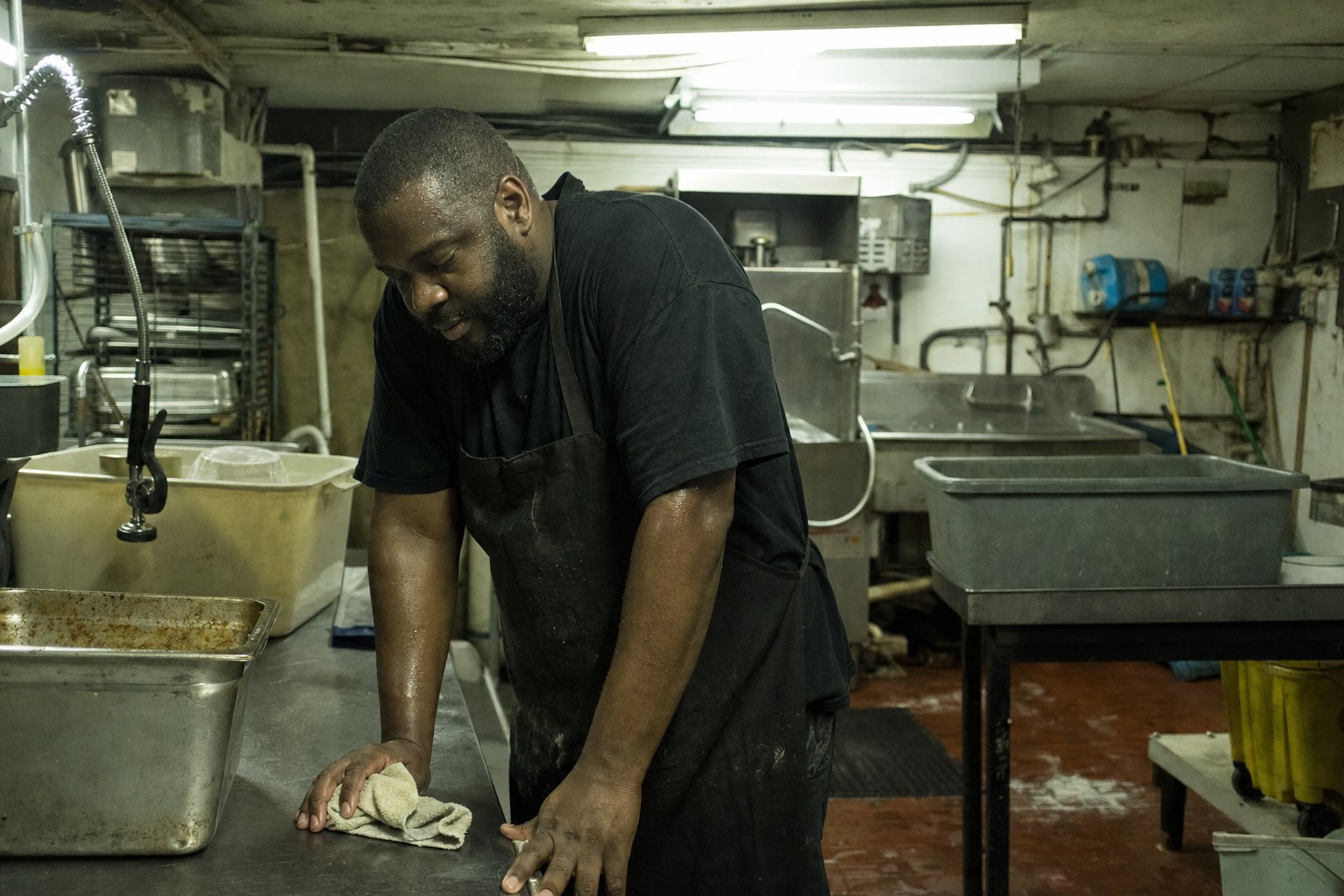 Exhausted cook cleaning down a dish area after service