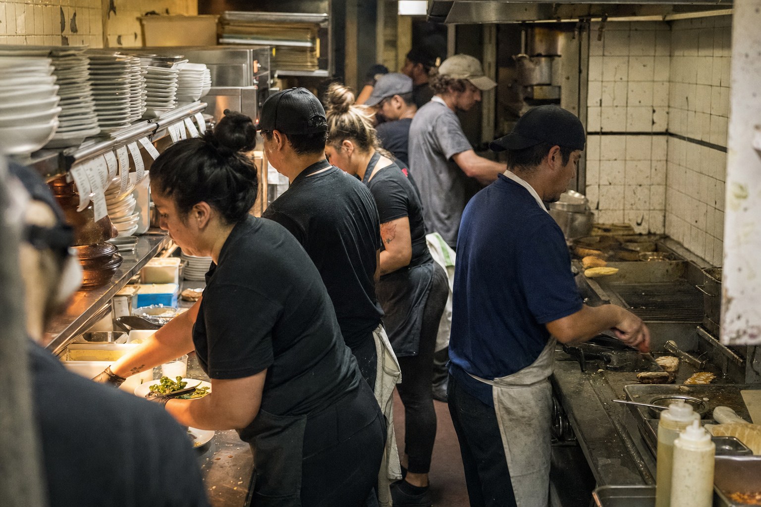 Diverse kitchen crew working a crowded line during dinner service