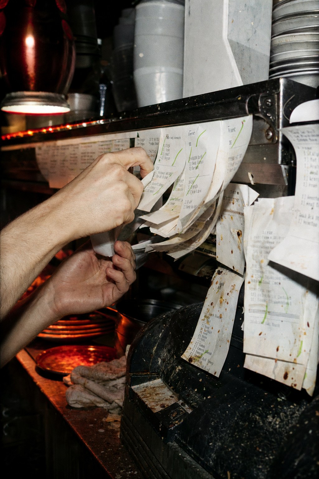 Hands pulling orders from a packed ticket rail