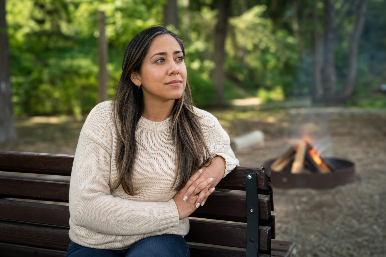 A person pausing quietly near a small outdoor fire