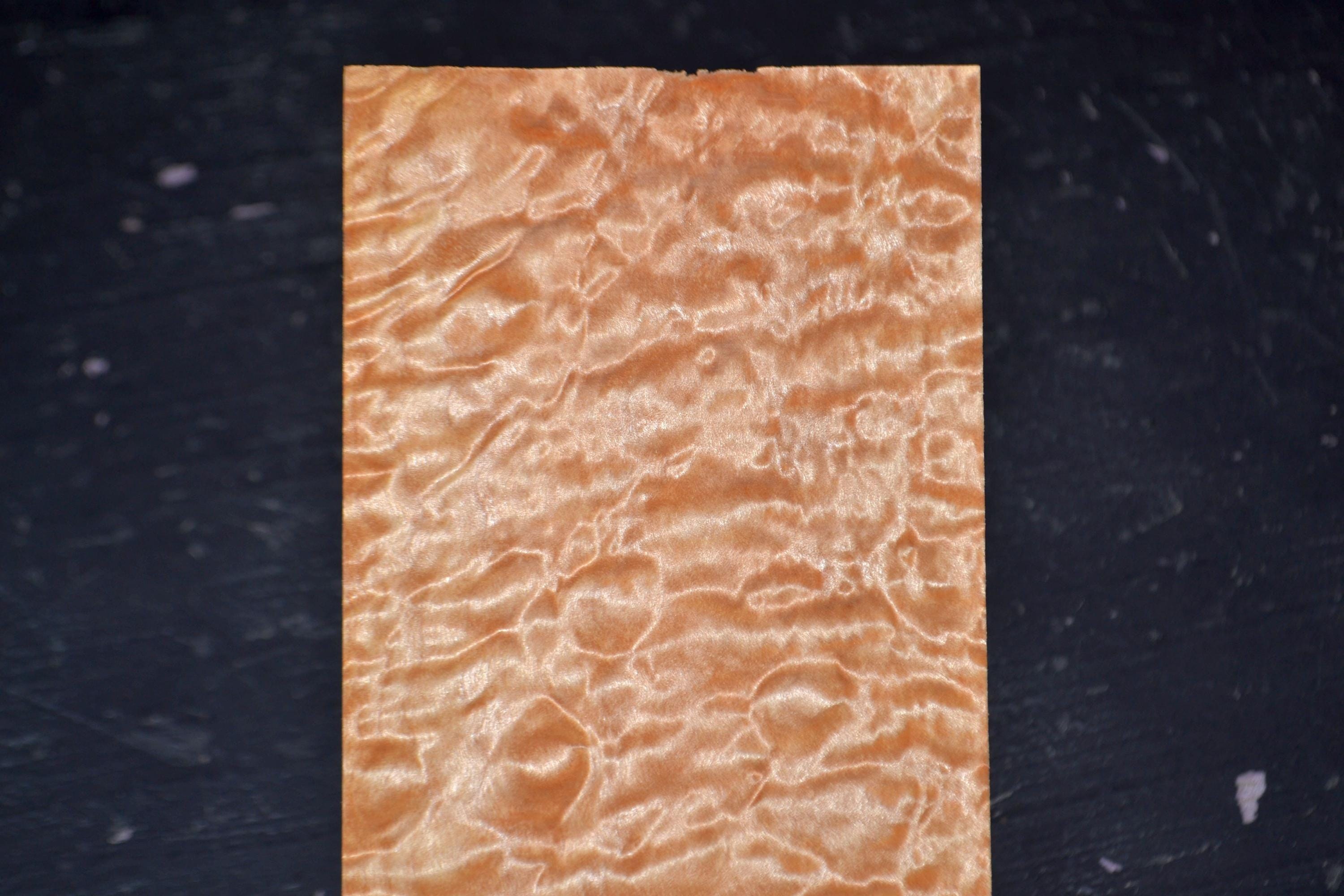 Quilted maple raw wood veneer sheet with a flowing grain pattern