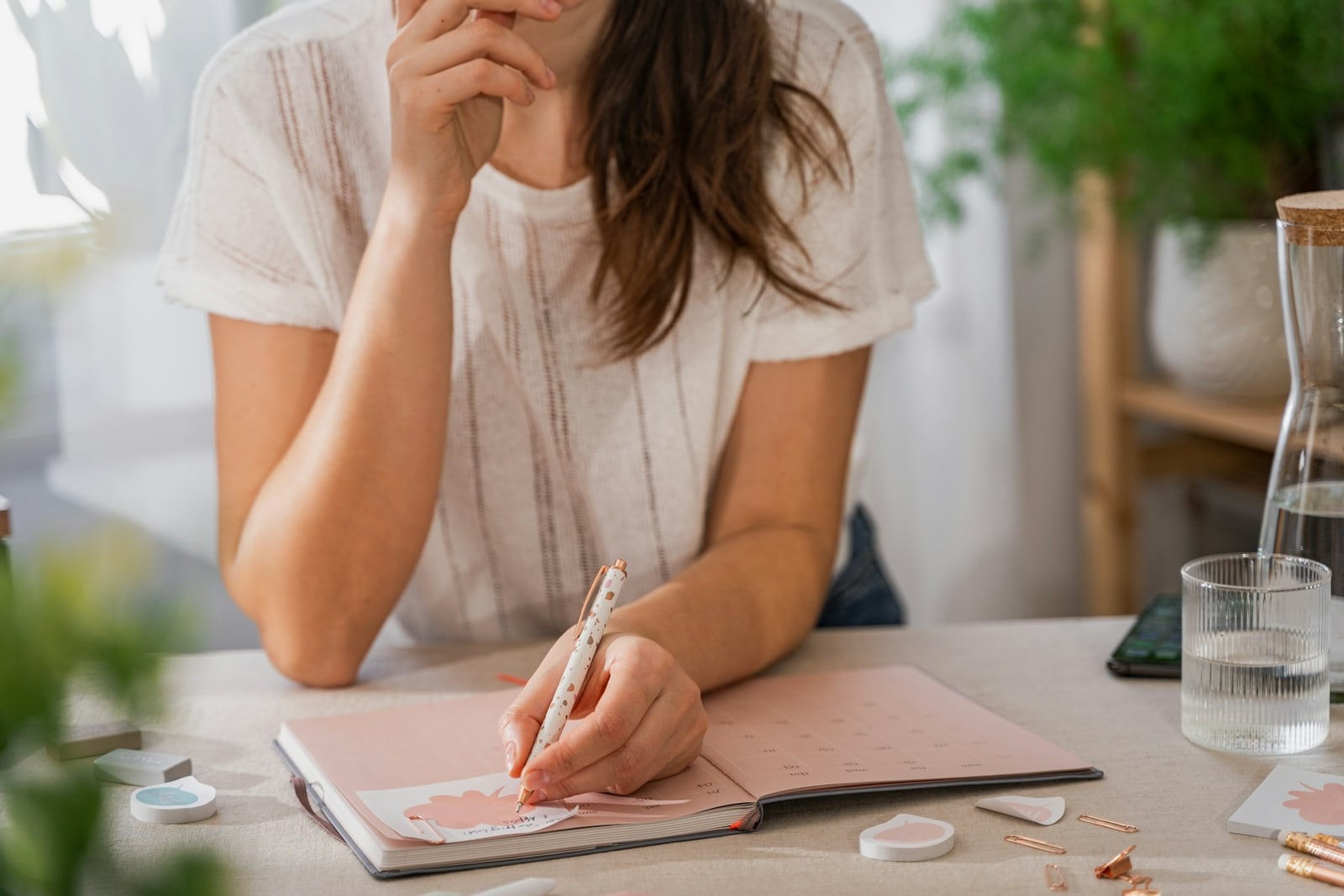 Person writing notes at a home desk before making an appointment