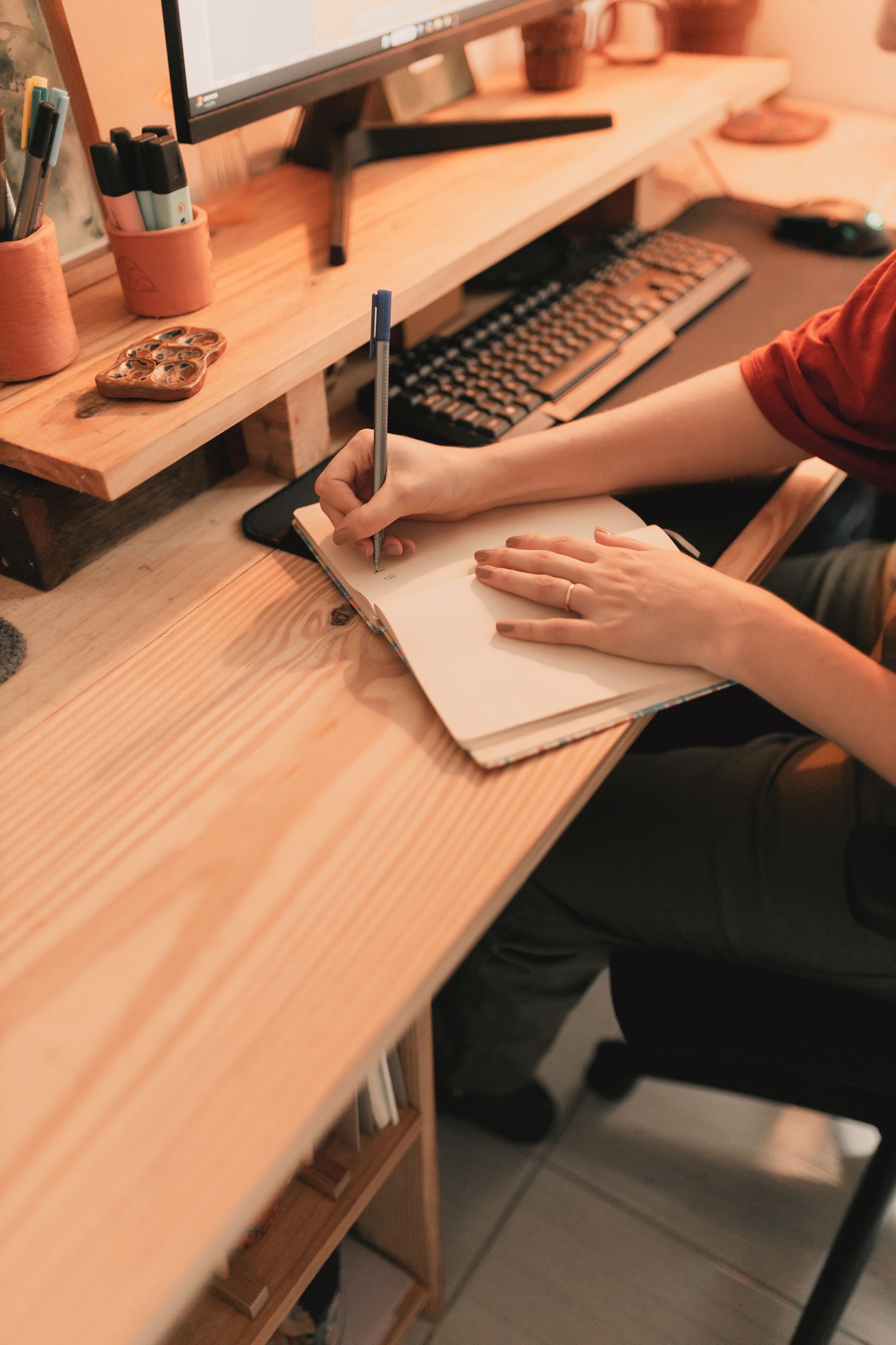 Person writing notes in a warm home workspace