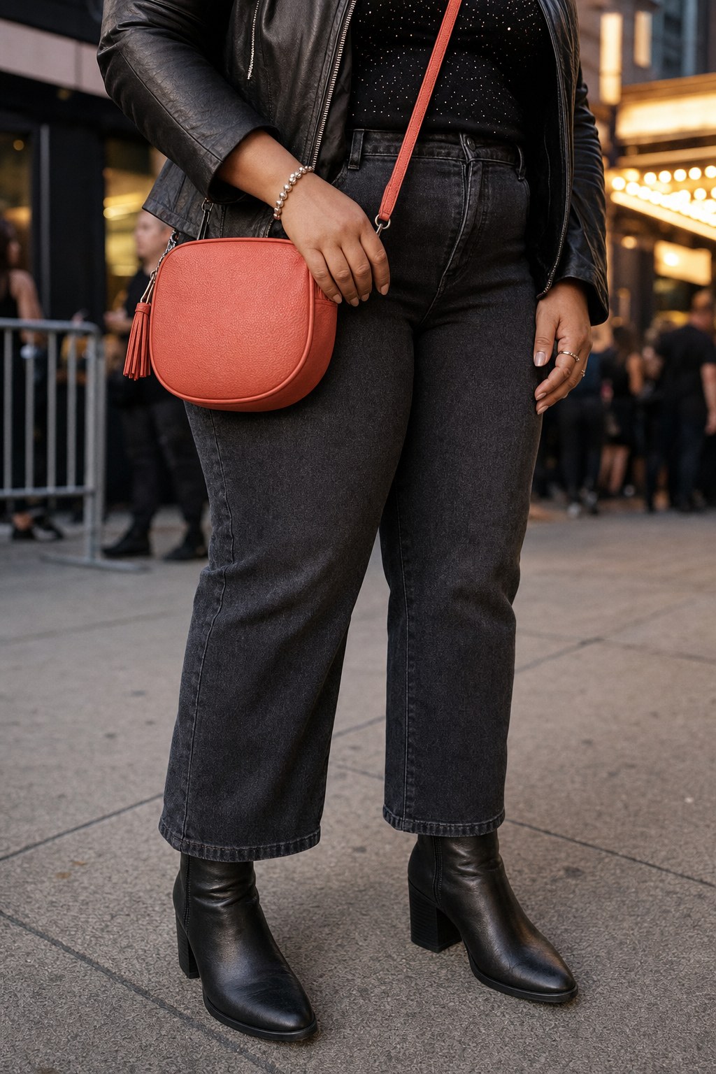 Black ankle boots, dark denim, and a coral crossbody bag outside a concert