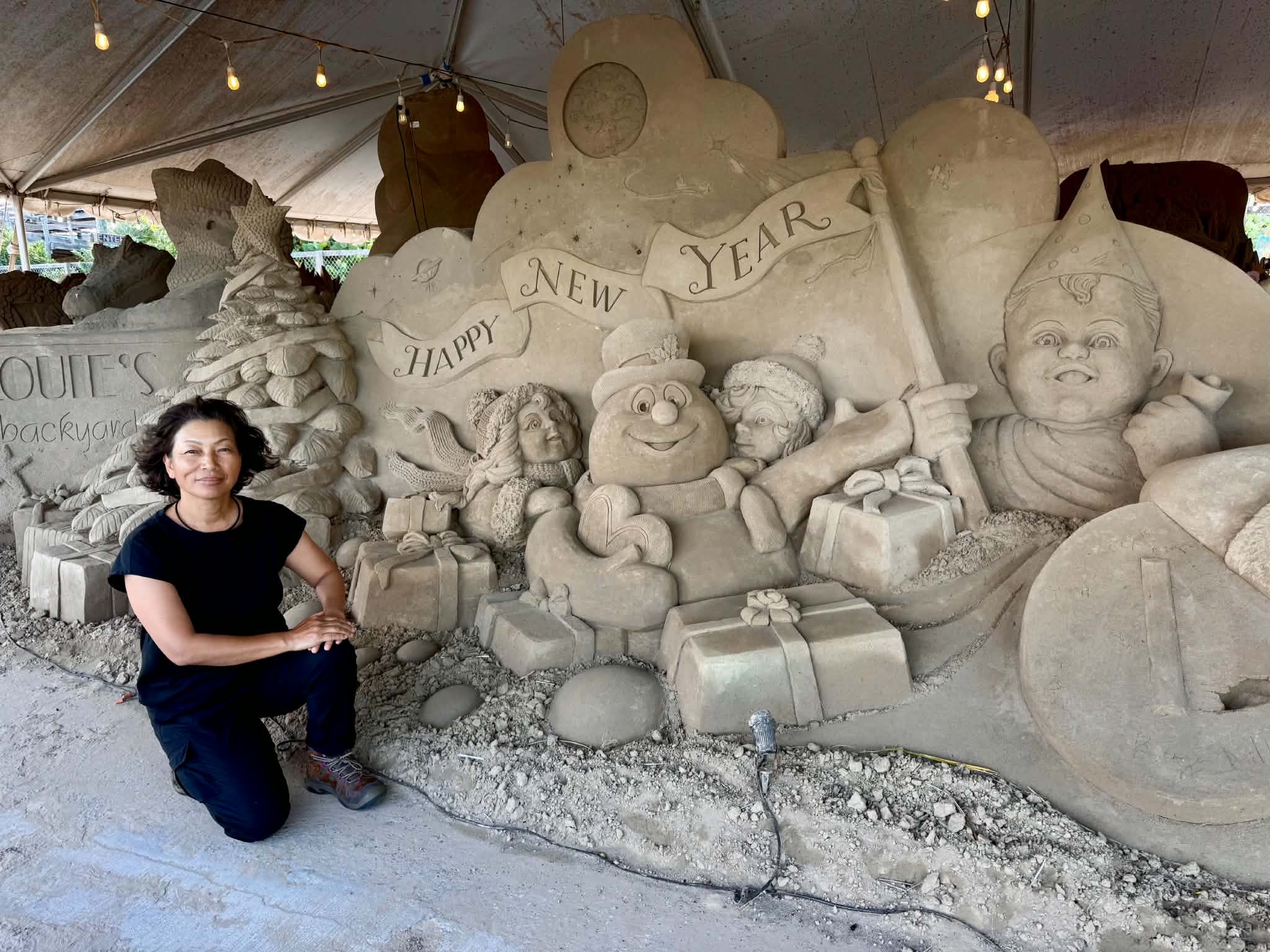 Yoshi Matsue beside Toasty the SandMan and the New Year Baby in the holiday sculpture
