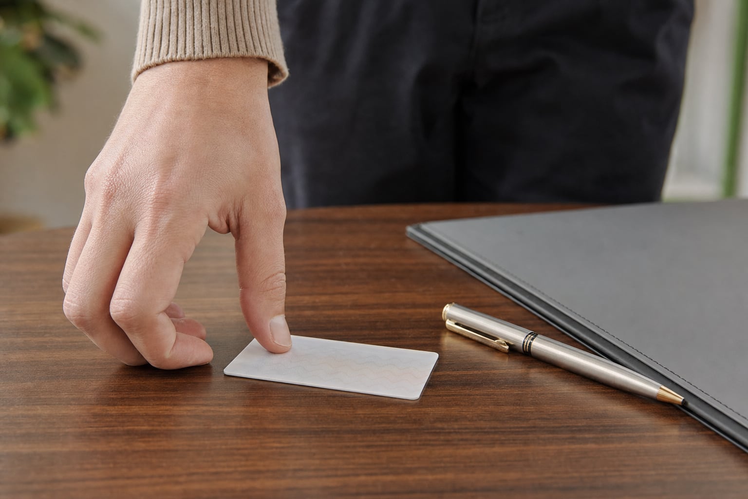 Person placing a photo identification card beside a pen and folder