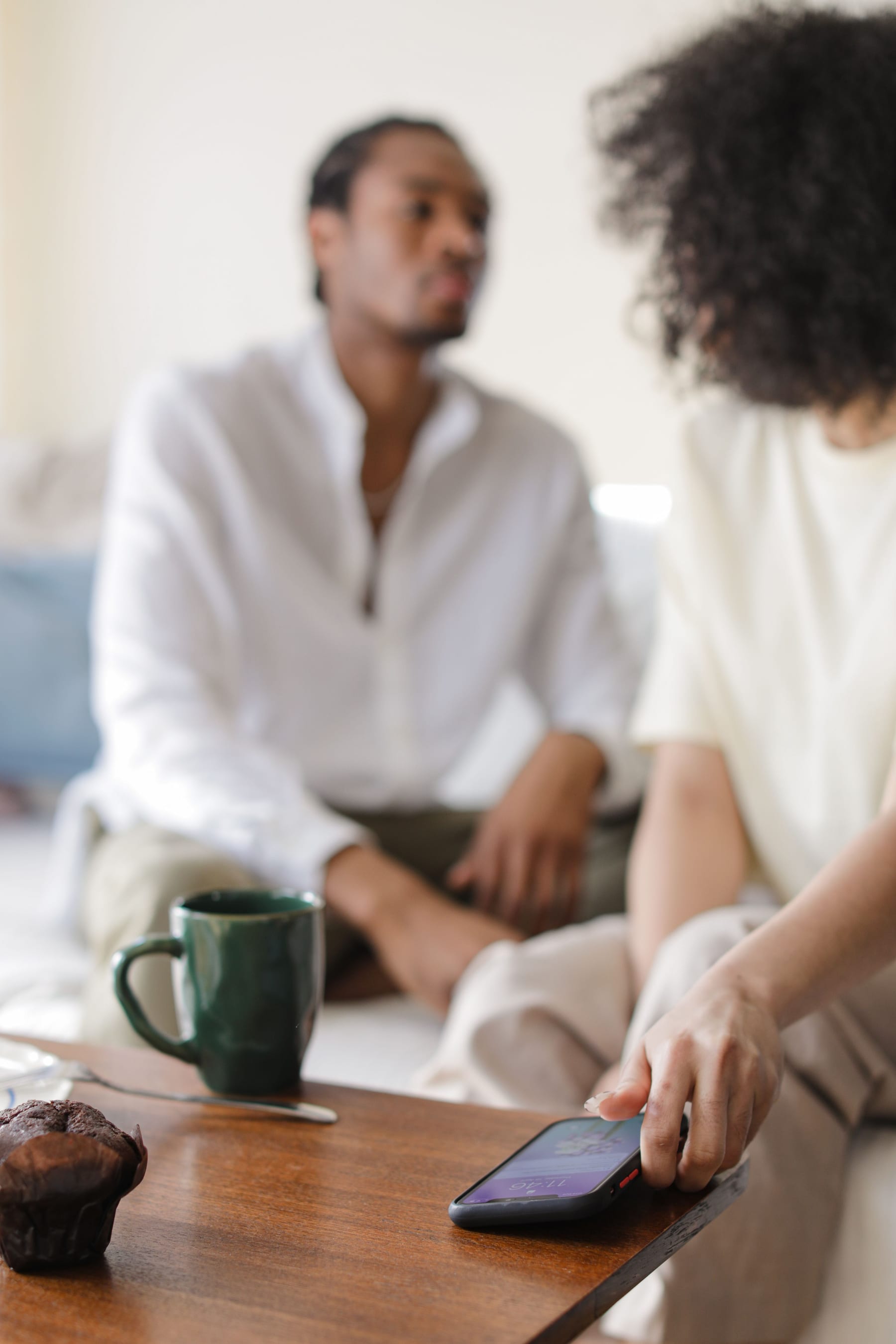 Two people talking at a table with a phone set down between them