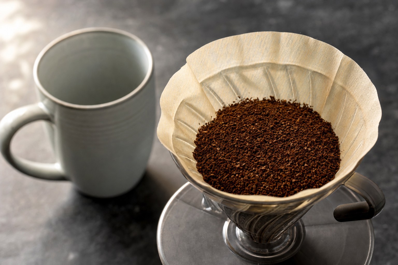 Medium coffee grounds in a paper filter inside a pour-over dripper